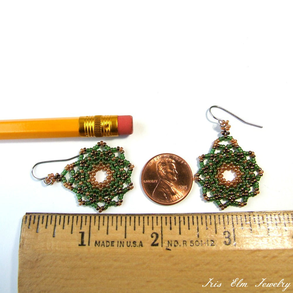 Pair of green beaded earrings next to a penny and a pencil, with a ruler for scale on a white background. Iris Elm Jewelry branding visible.