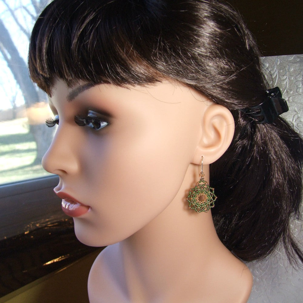 Mannequin head with dark hair styled in a ponytail and wearing green mandala earrings.