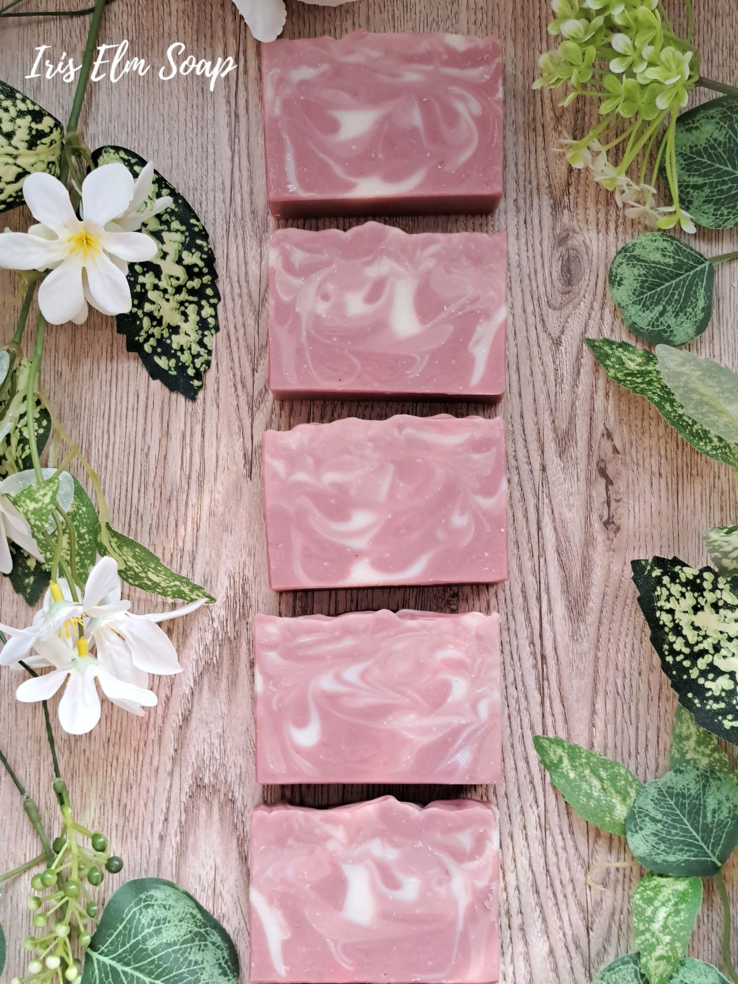 Pink unscented rose clay handmade vegan soap bars on a wooden surface with green leaves and flowers