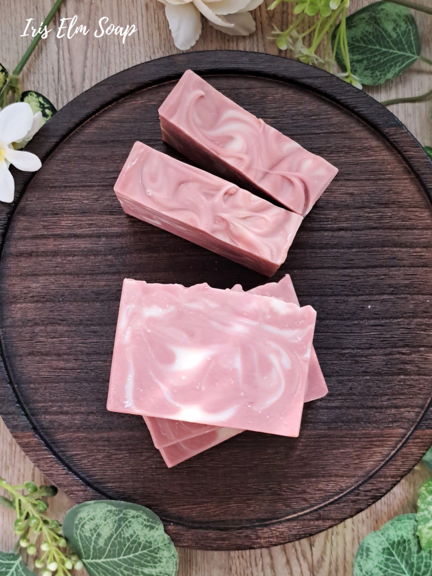 Pink marbled unscented rose clay handmade soap bars on a wooden board with greenery around
