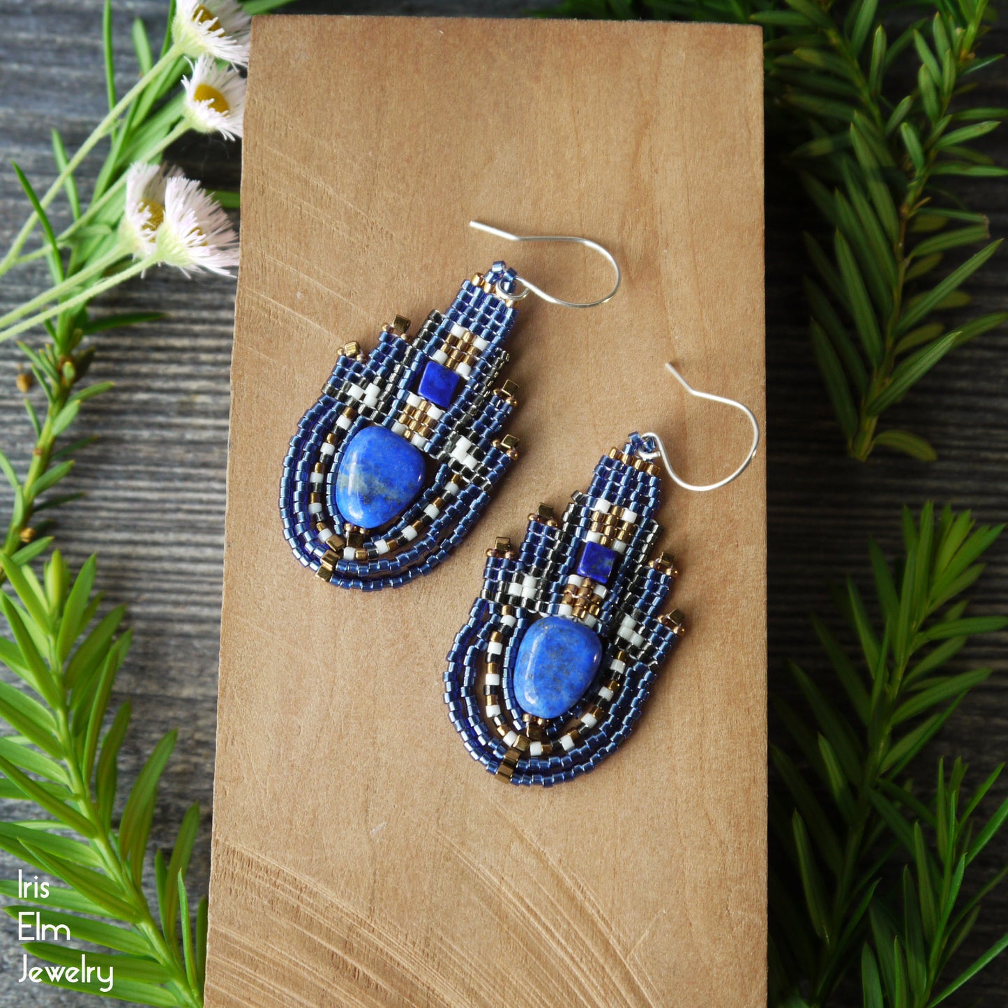 Blue lapis lazuli boho beaded earrings with seed beads and sterling silver ear wires on a wooden surface with greenery around