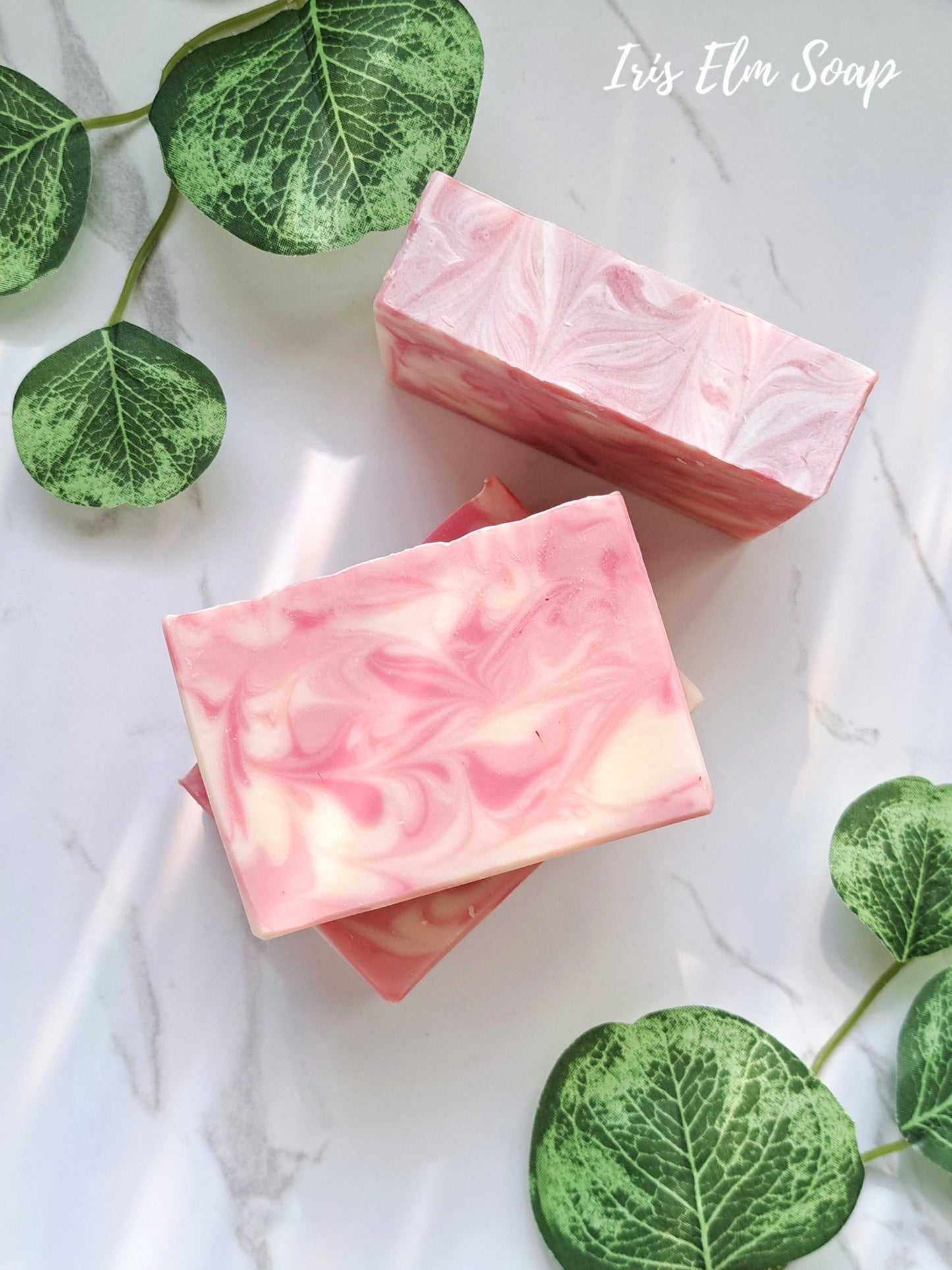 Two pink soap citrus love spell bars with green leaves on a light background