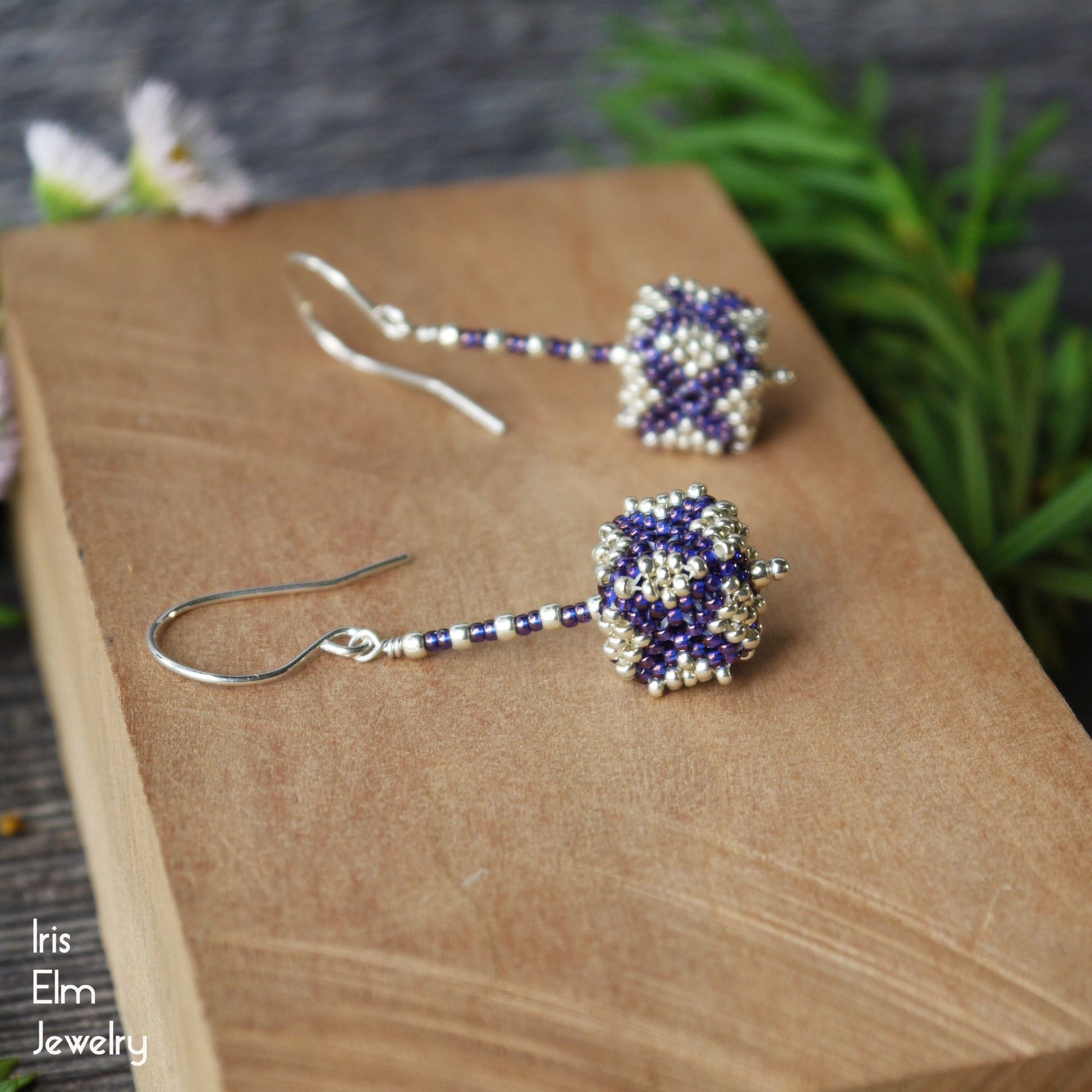 Beaded purple and silver seed bead cube shaped sterling silver handmade earrings on a wooden surface with a natural background