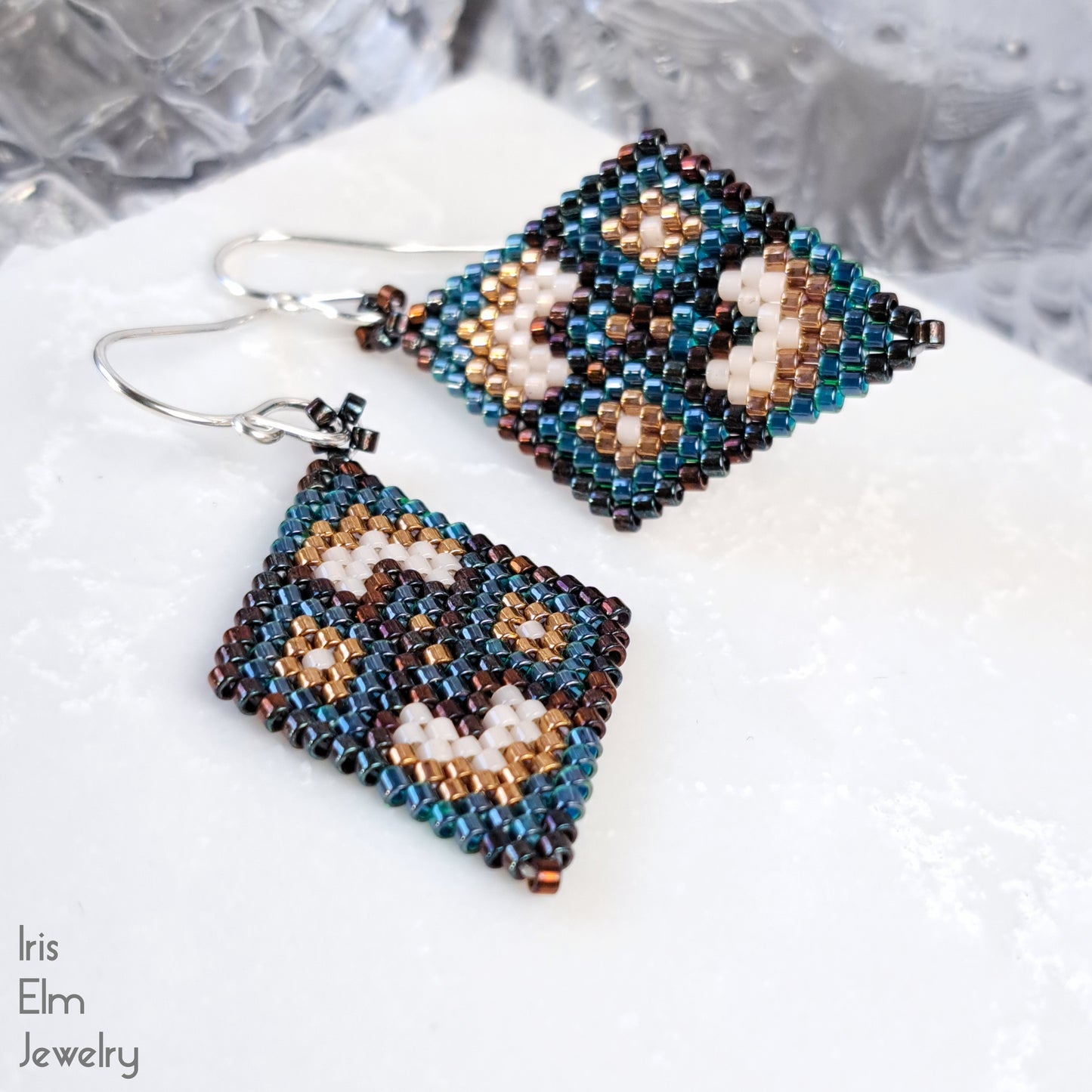 Pair of green and bronze handmade beaded diamond shape earrings on a white surface with 'Iris Elm Jewelry' branding.