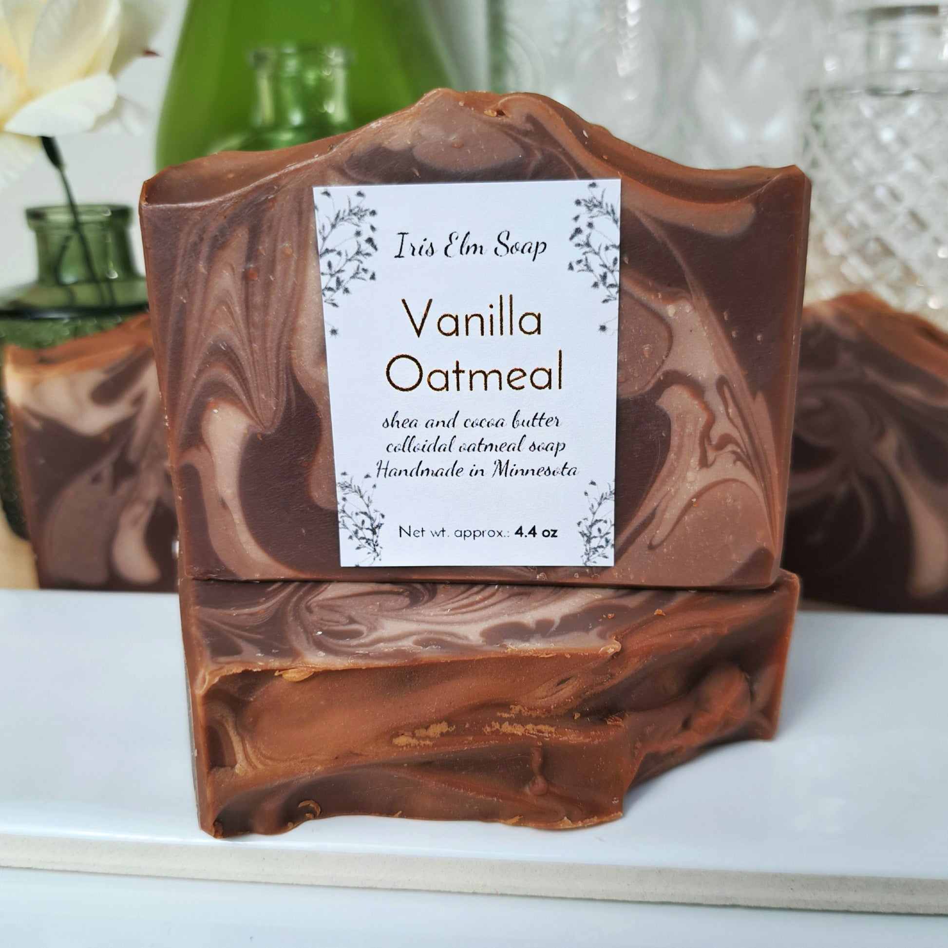Vanilla oatmeal handmade soap bar with a Iris Elm Soap label on a white surface