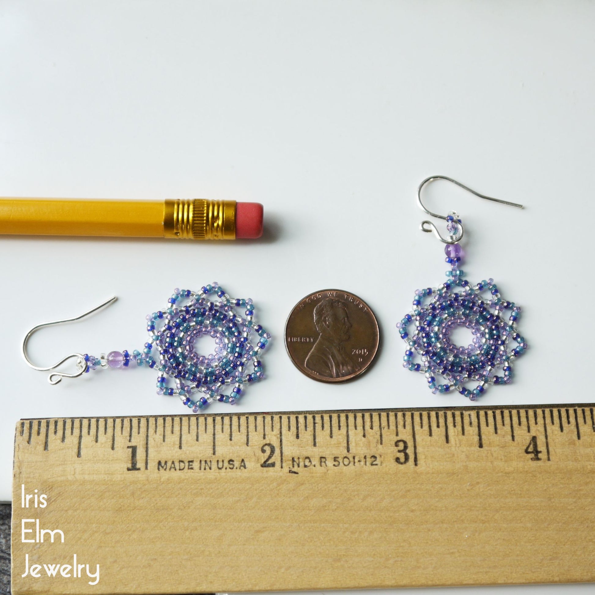 Pair of 2 inch long beaded earrings next to a pencil and penny on a white background, with 'Iris Elm Jewelry' branding.