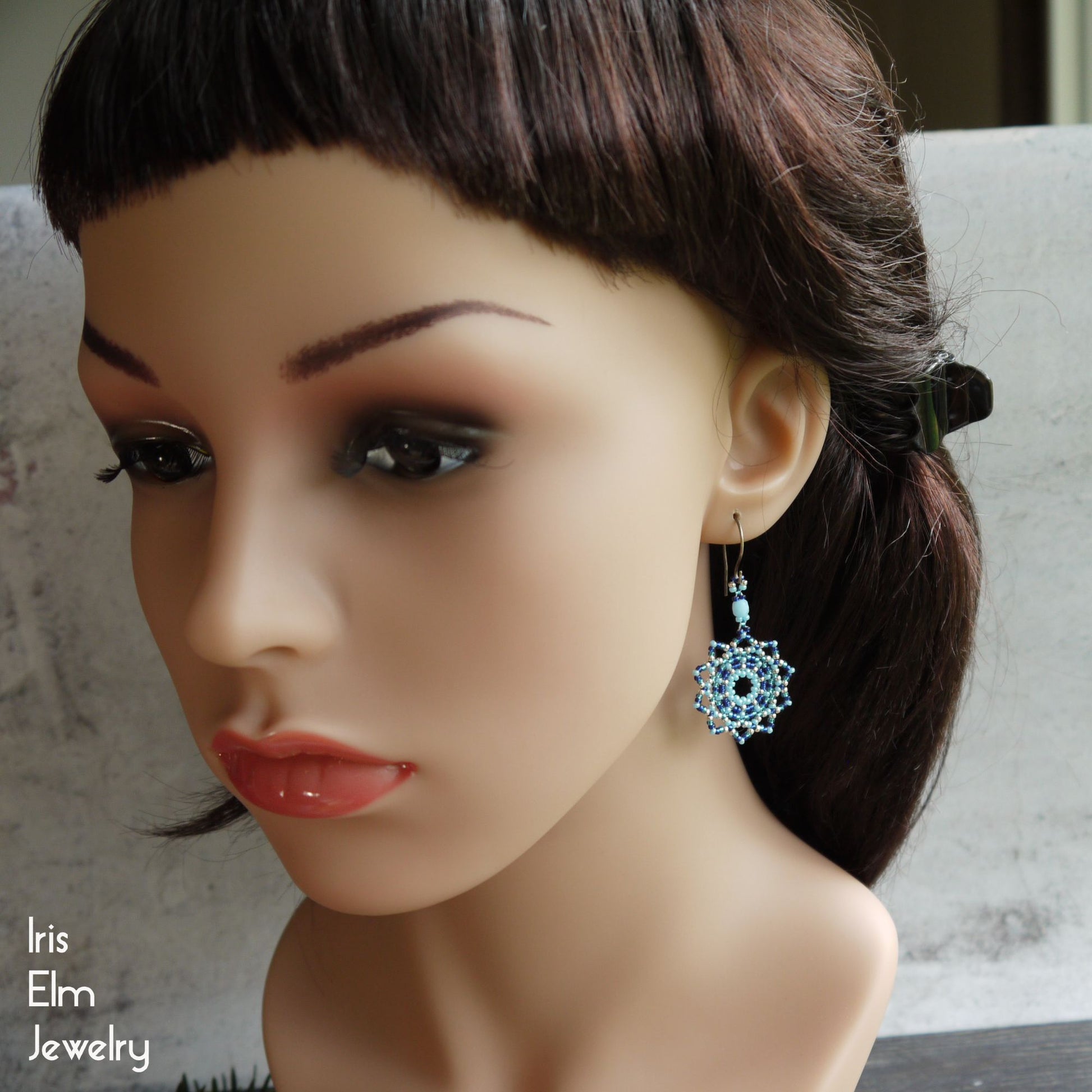 Mannequin head with a blue earring on a neutral background