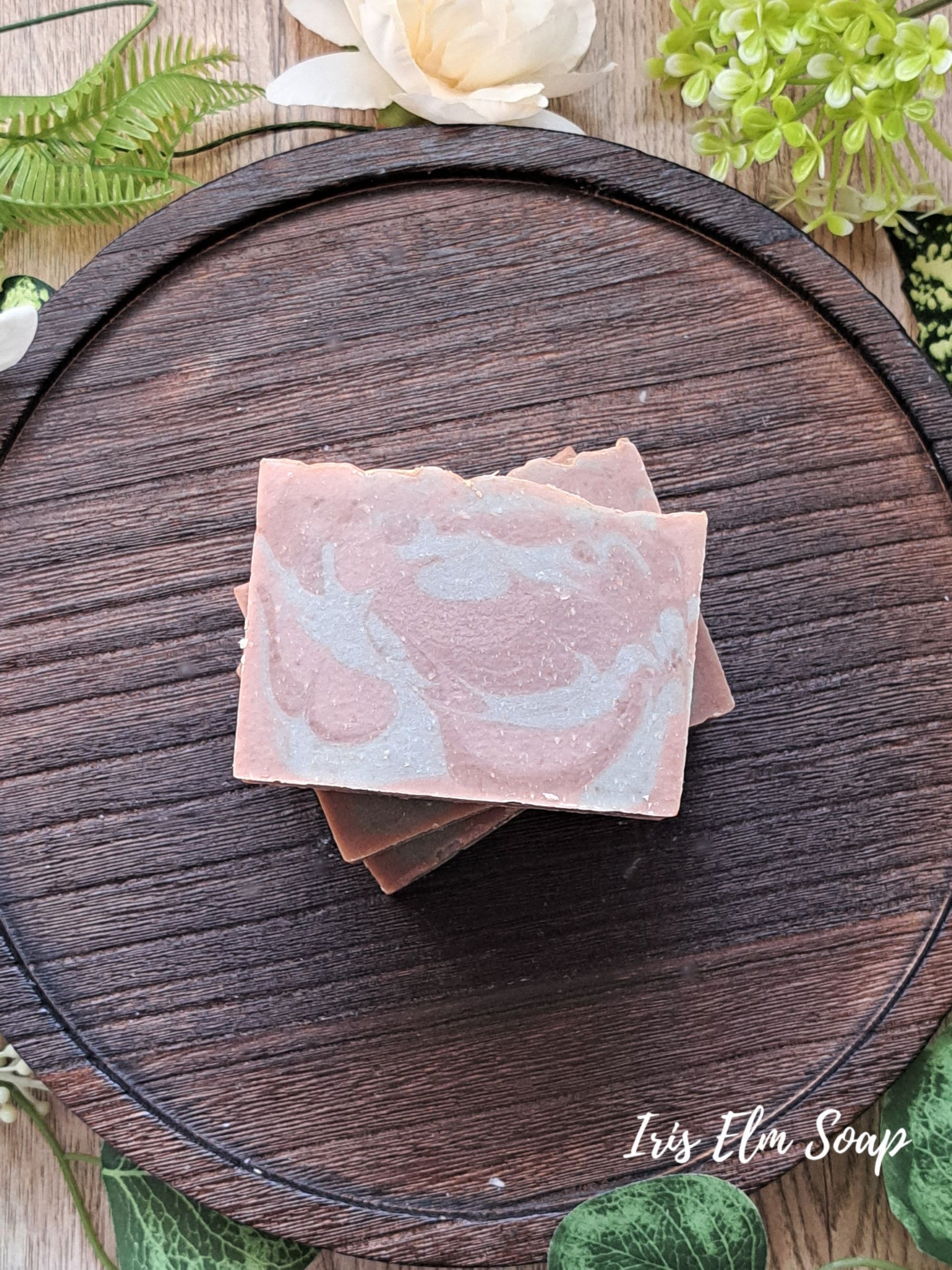 green and brown marbled pistachio caramel cream handmade soap on a wooden board with greenery in the background