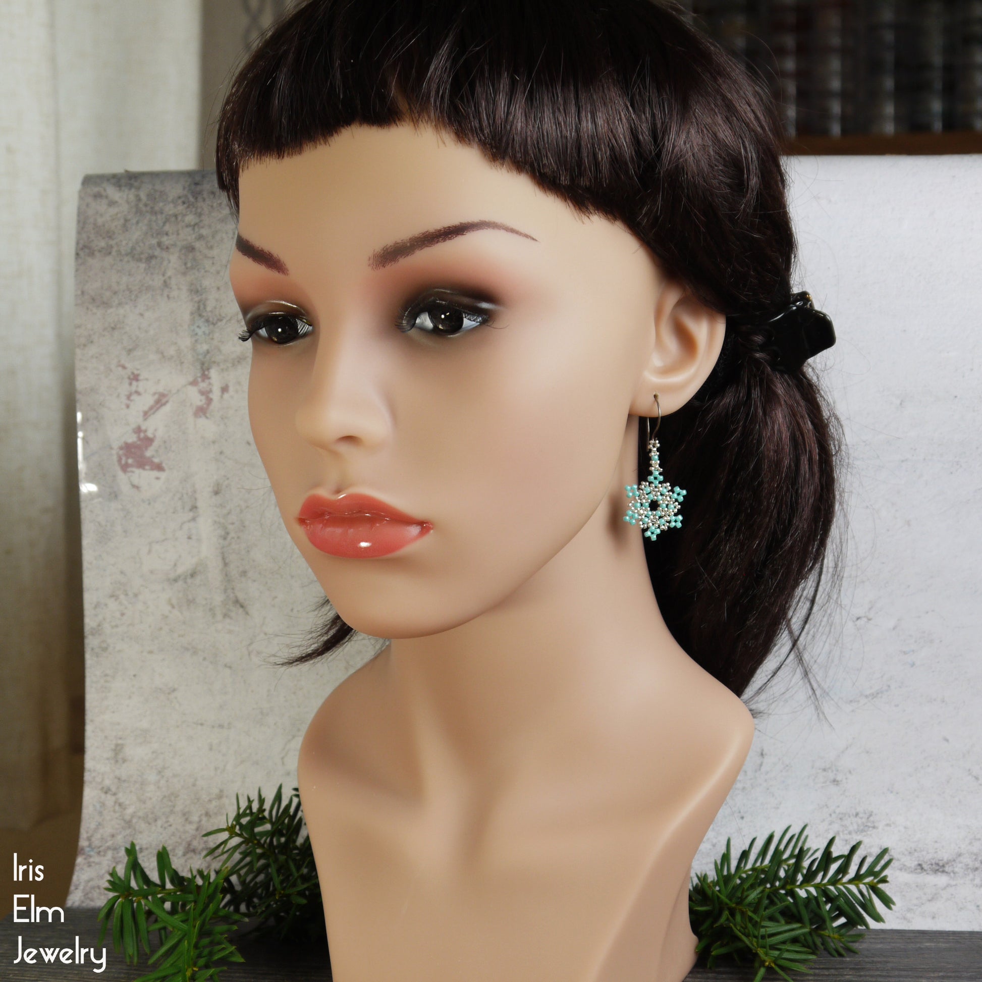 Mannequin head with dark hair and snowflake seed bead earrings, featuring 'Iris Elm Jewelry' branding.