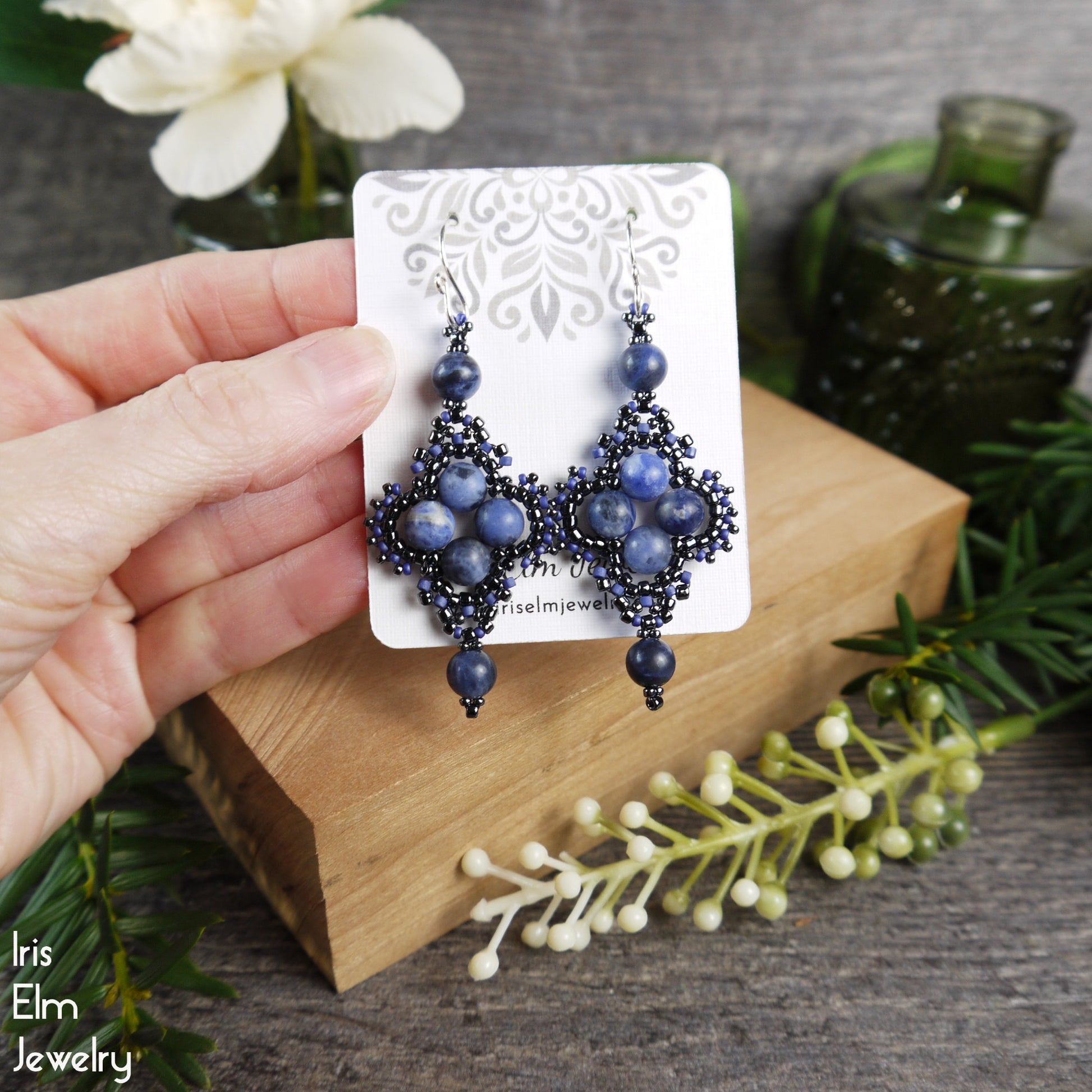 Blue sodalite beaded earrings on a card held by a hand with a natural background