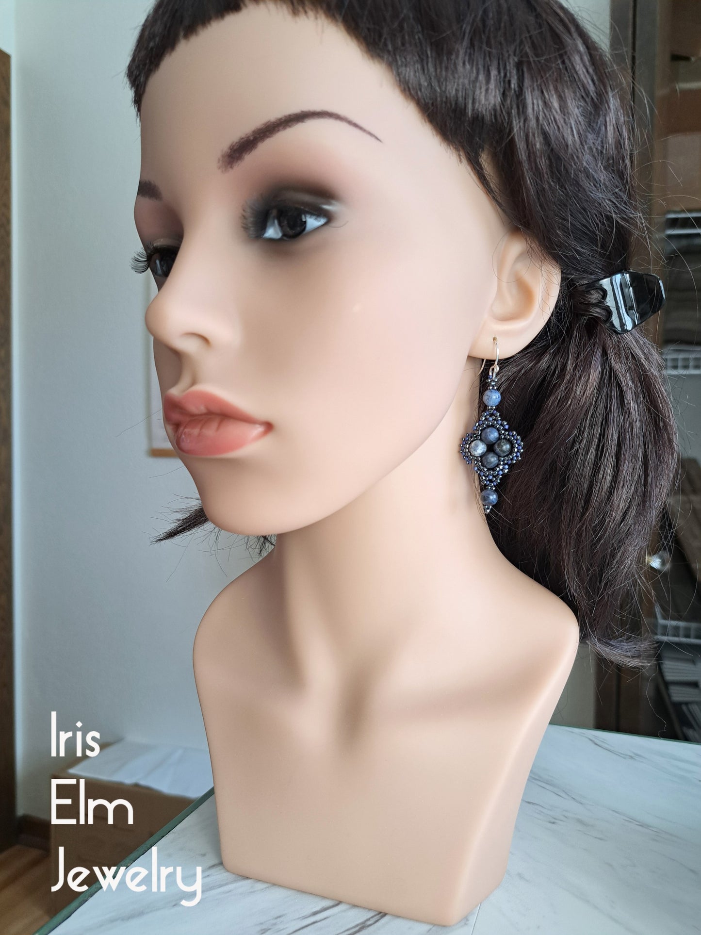 Mannequin head with sodalite earrings on a blurred indoor background