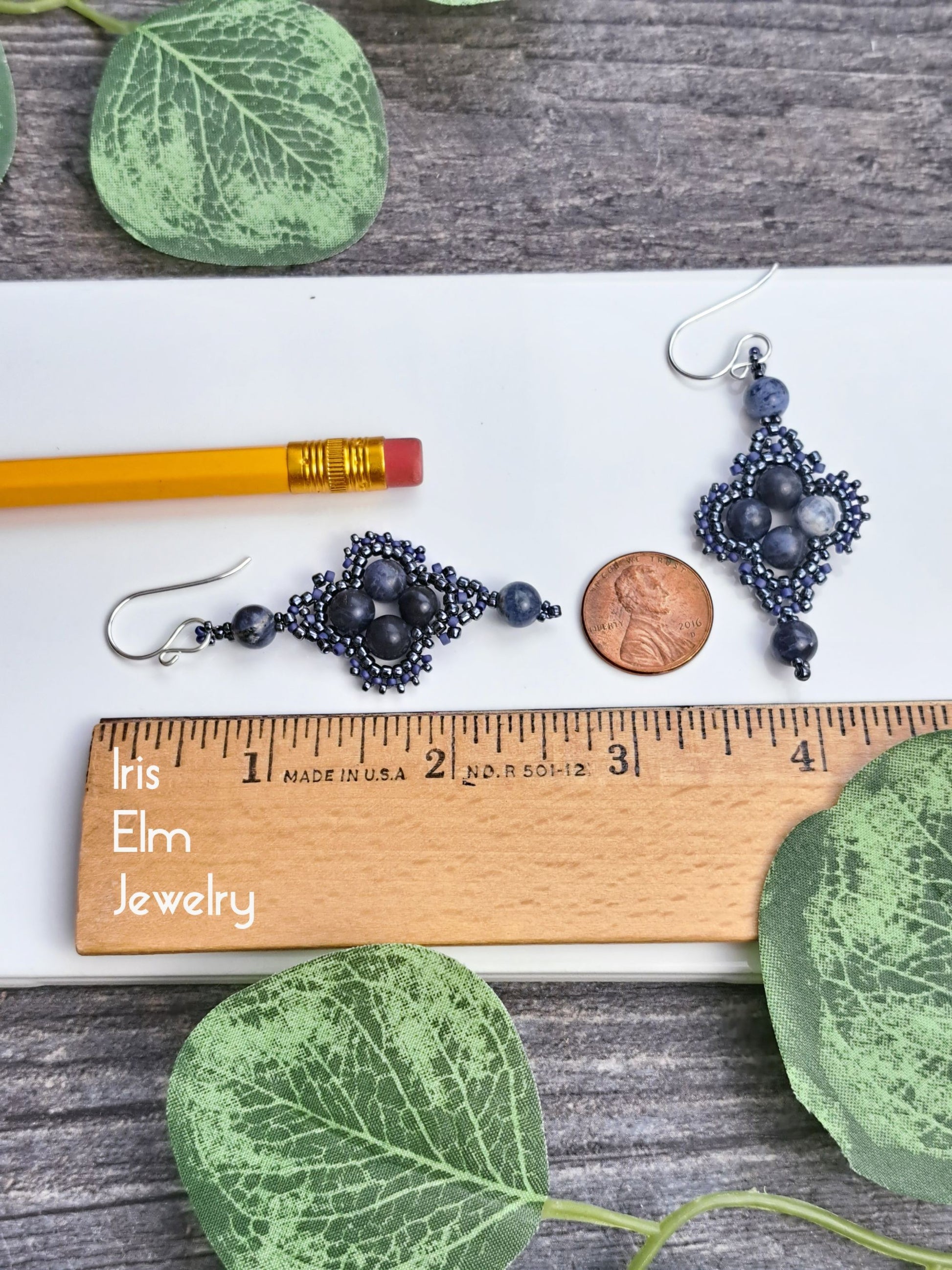 Pair of 2.25 inch long sodalite beaded earrings on a wooden ruler with leaves and a pencil for scale.
