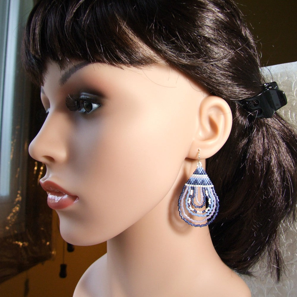 Mannequin head with dark hair and a blue beaded earring.