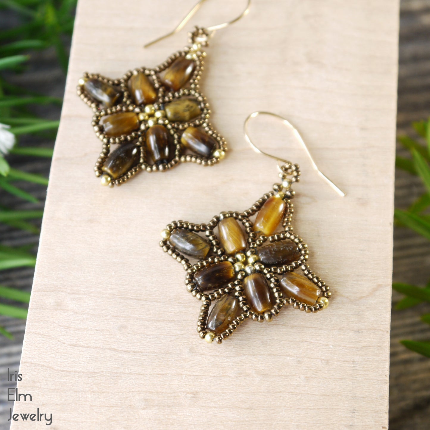 beadwork earrings with brown tiger stones stitched together on a wooden block with 'Iris Elm Jewelry' branding.