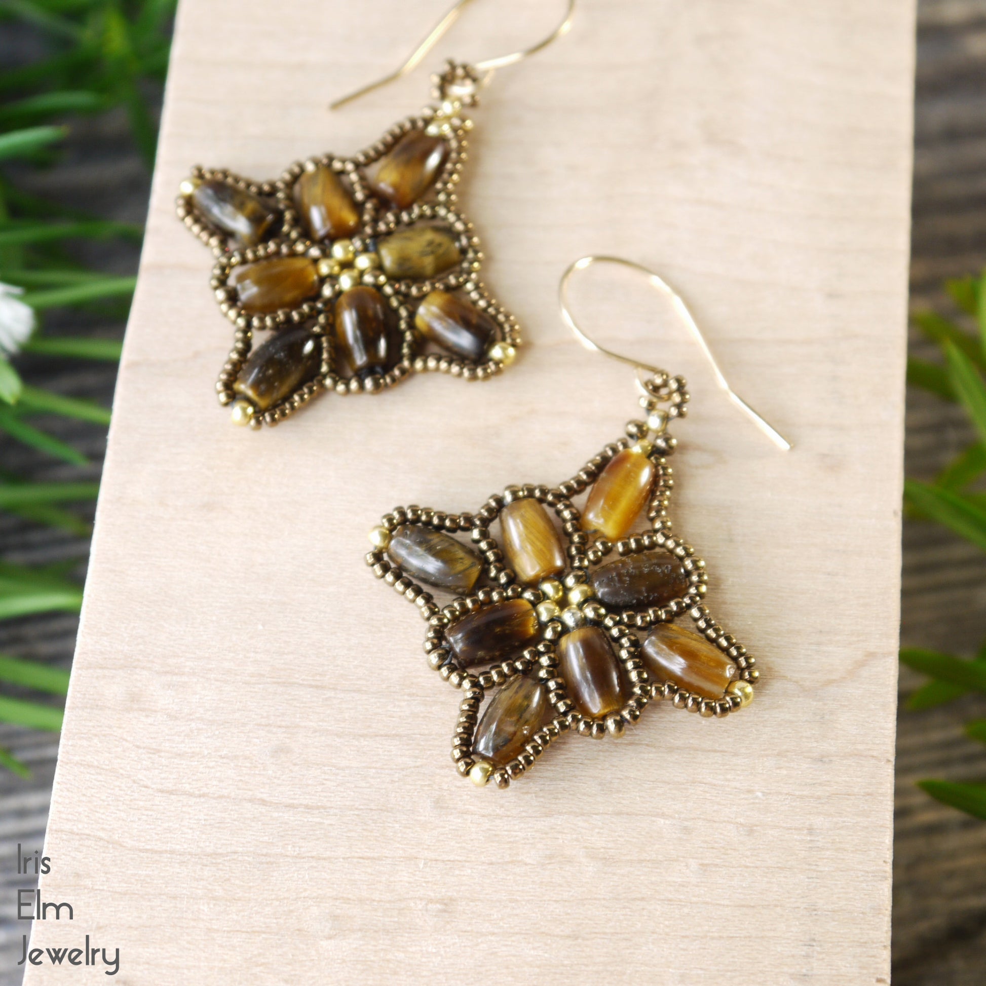 beadwork earrings with brown tiger stones stitched together on a wooden block with 'Iris Elm Jewelry' branding.