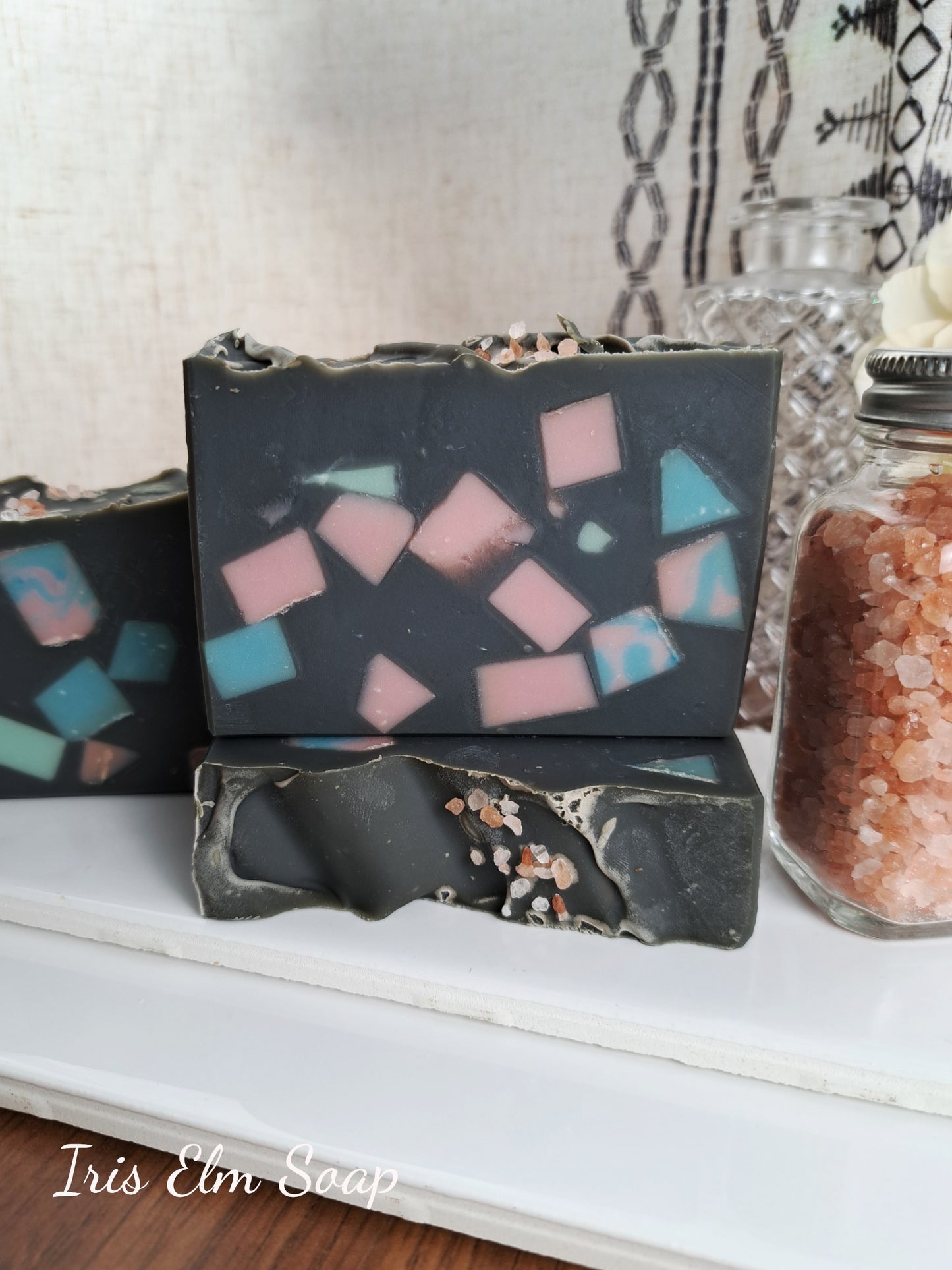 Three homemade soap bars with mosaic designs on a white surface, with 'Iris Elm Soap' branding.