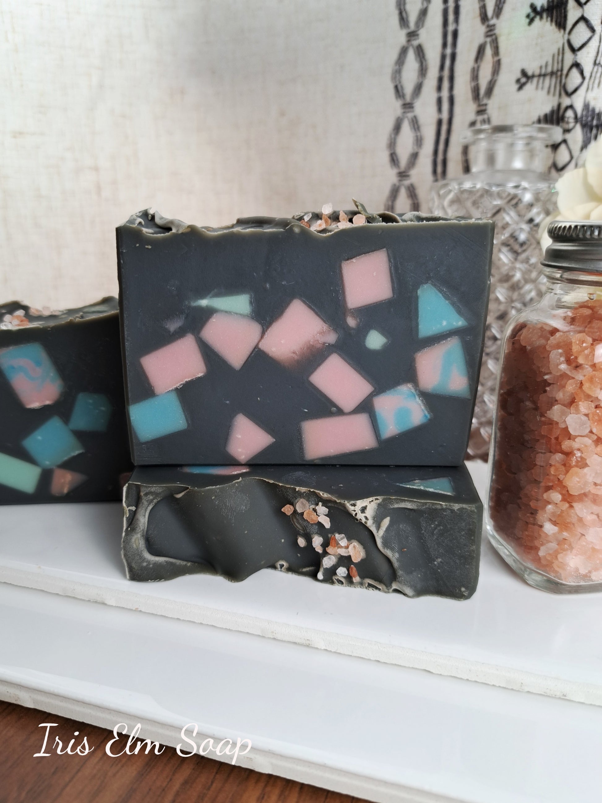 Three homemade soap bars with mosaic designs on a white surface, with 'Iris Elm Soap' branding.