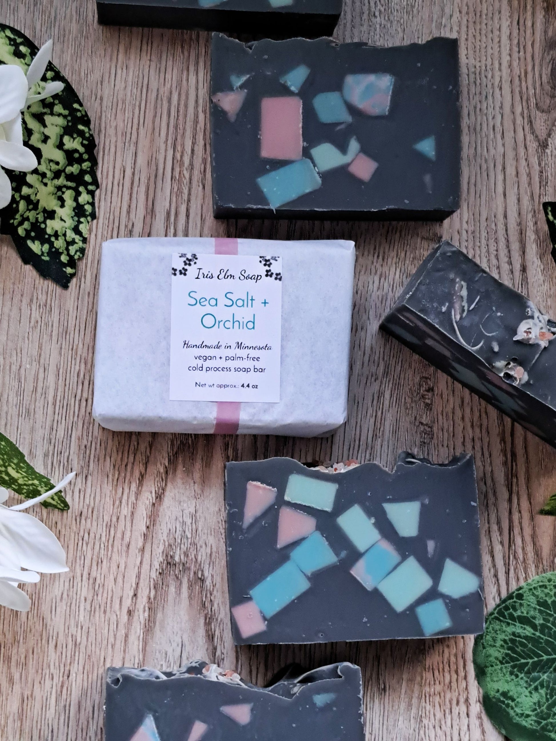 Sea Salt + Orchid soap bar with decorative soap pieces on a wooden surface