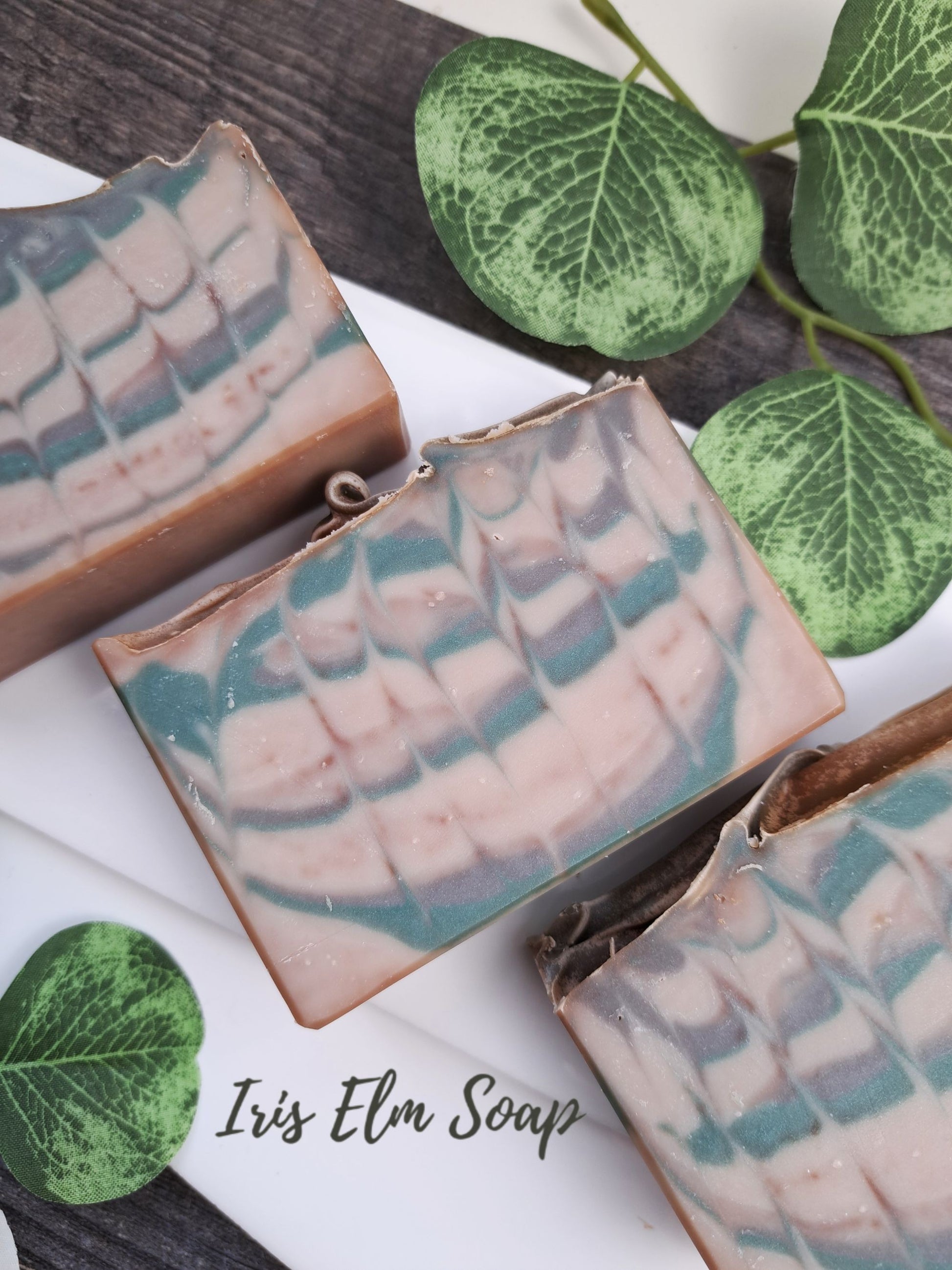 Three bars of Iris Elm Soap with green leaves on a white background