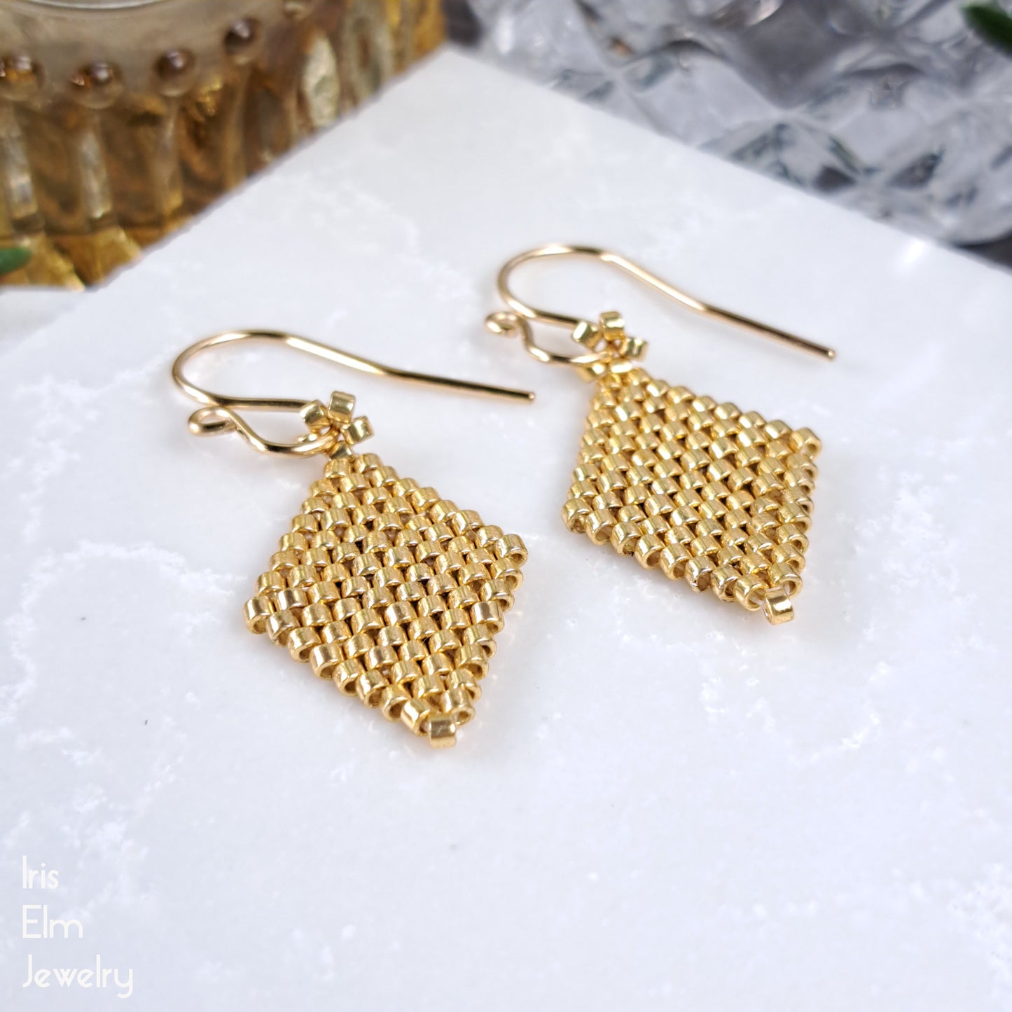 Gold seed bead beadwoven earrings on a white surface with 'The Elm Jewelry' branding.