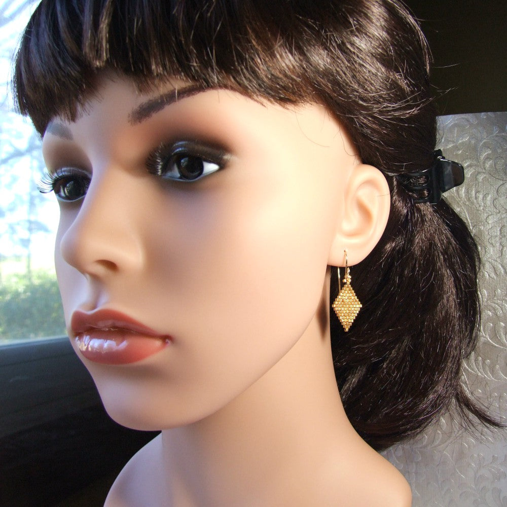 Mannequin head with dark hair and gold earrings on a neutral background