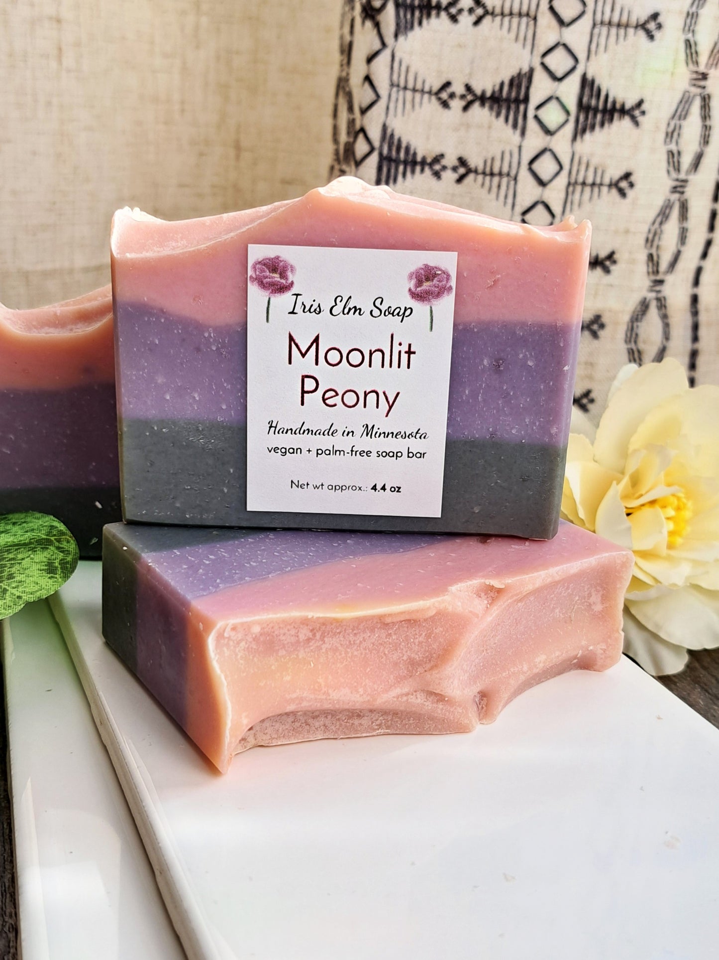 Two layered soap bars with a 'Moonlit Peony' label on a white surface.