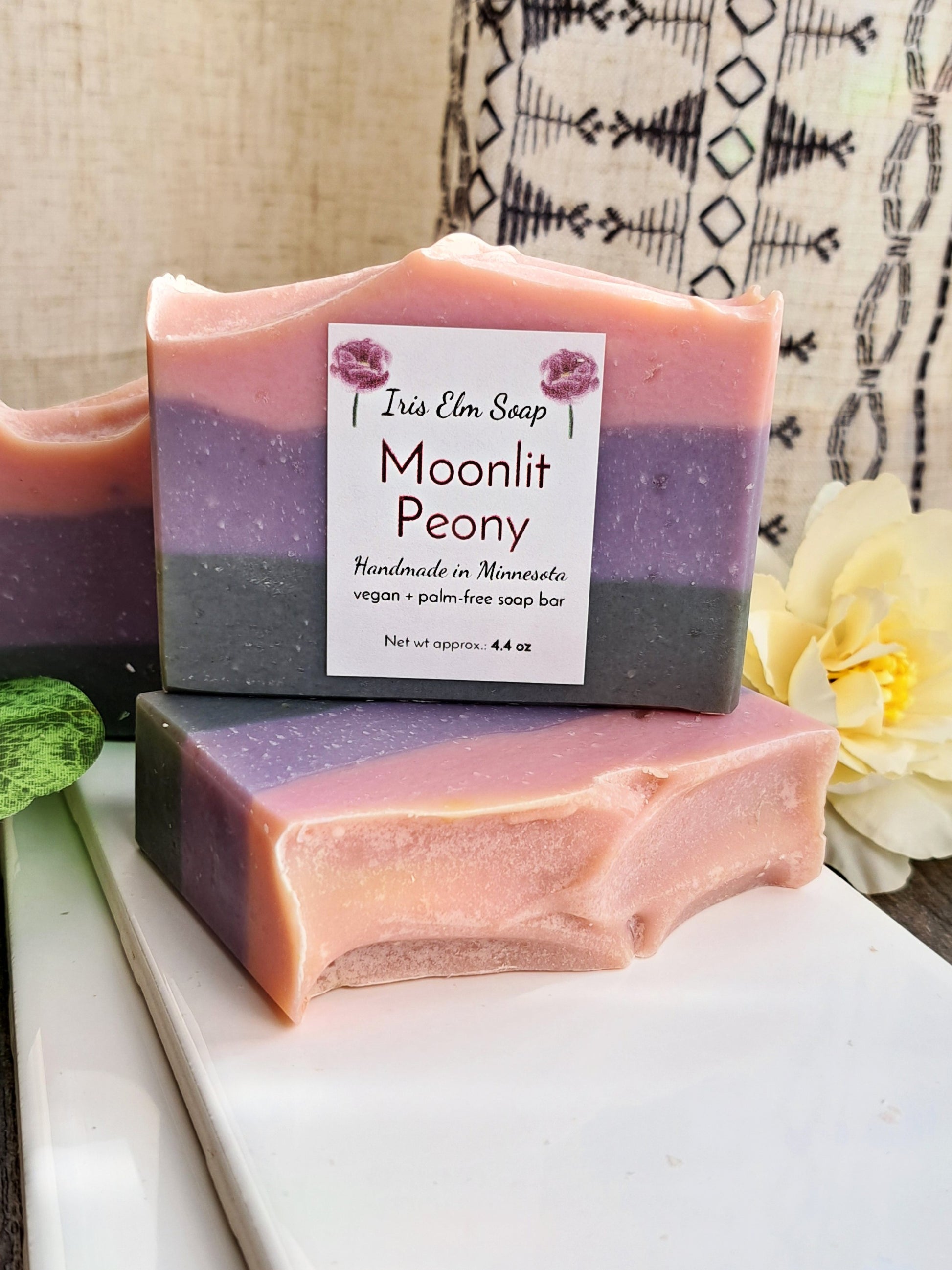 Two layered soap bars with a 'Moonlit Peony' label on a white surface.
