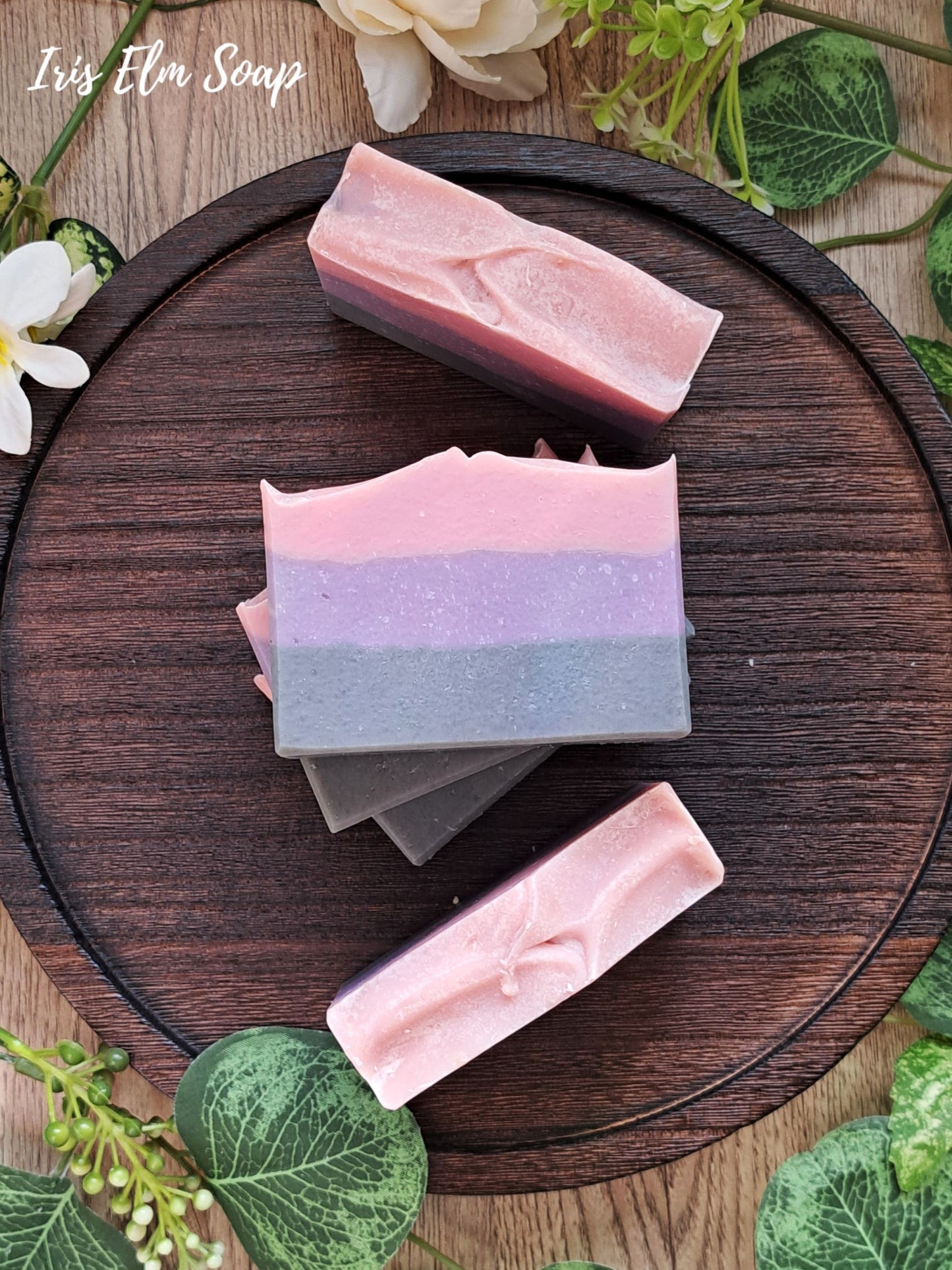 Three layered moonlit peony handmade soap bars on a wooden board with greenery around