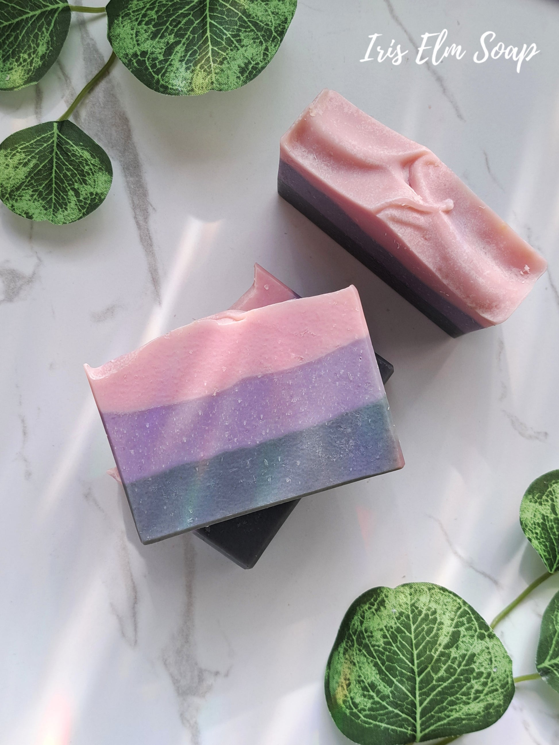 Three layered moonlit peony handmade soap bars on a marble surface with green leaves