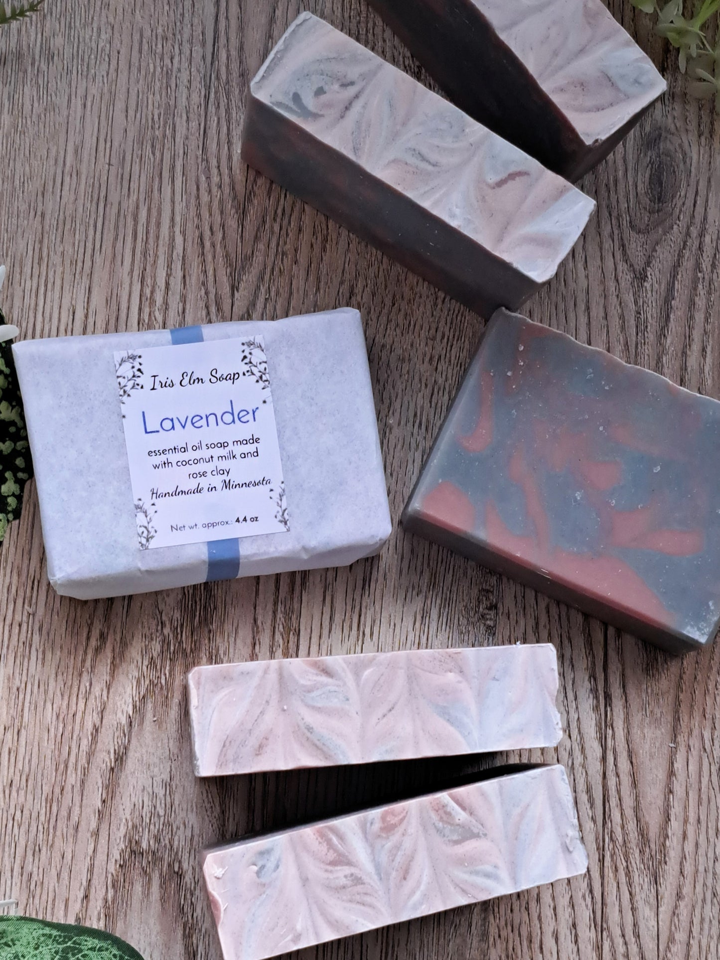 Handmade lavender essential oil soap bars on a wooden surface with 'Iris Elm Soap' packaging.
