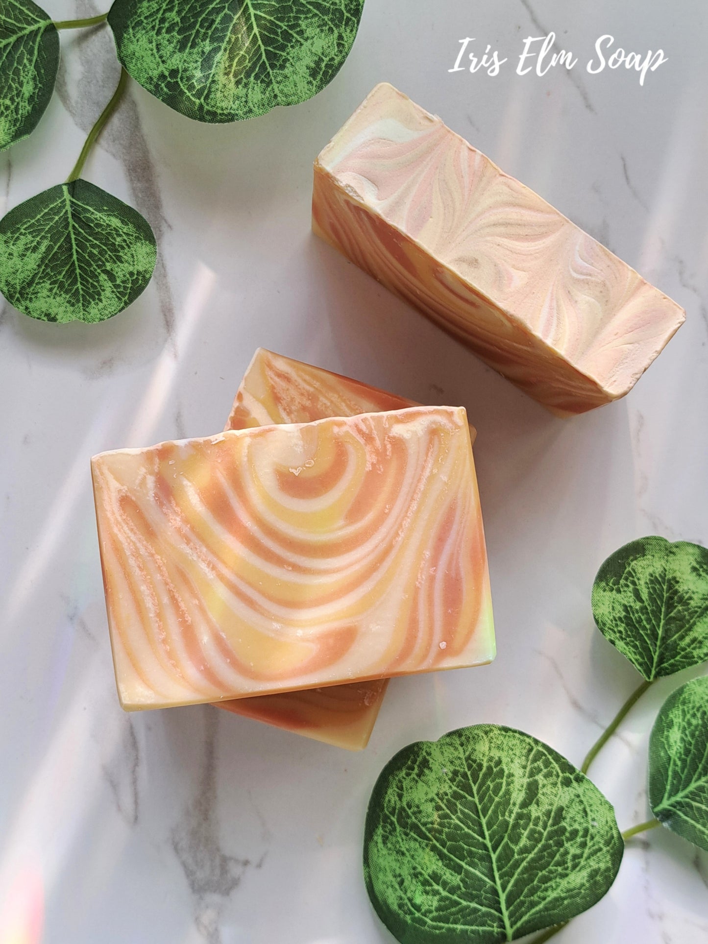 orange striped mango tangerine handmade soap on white marble surface with Iris Elm Soap branding