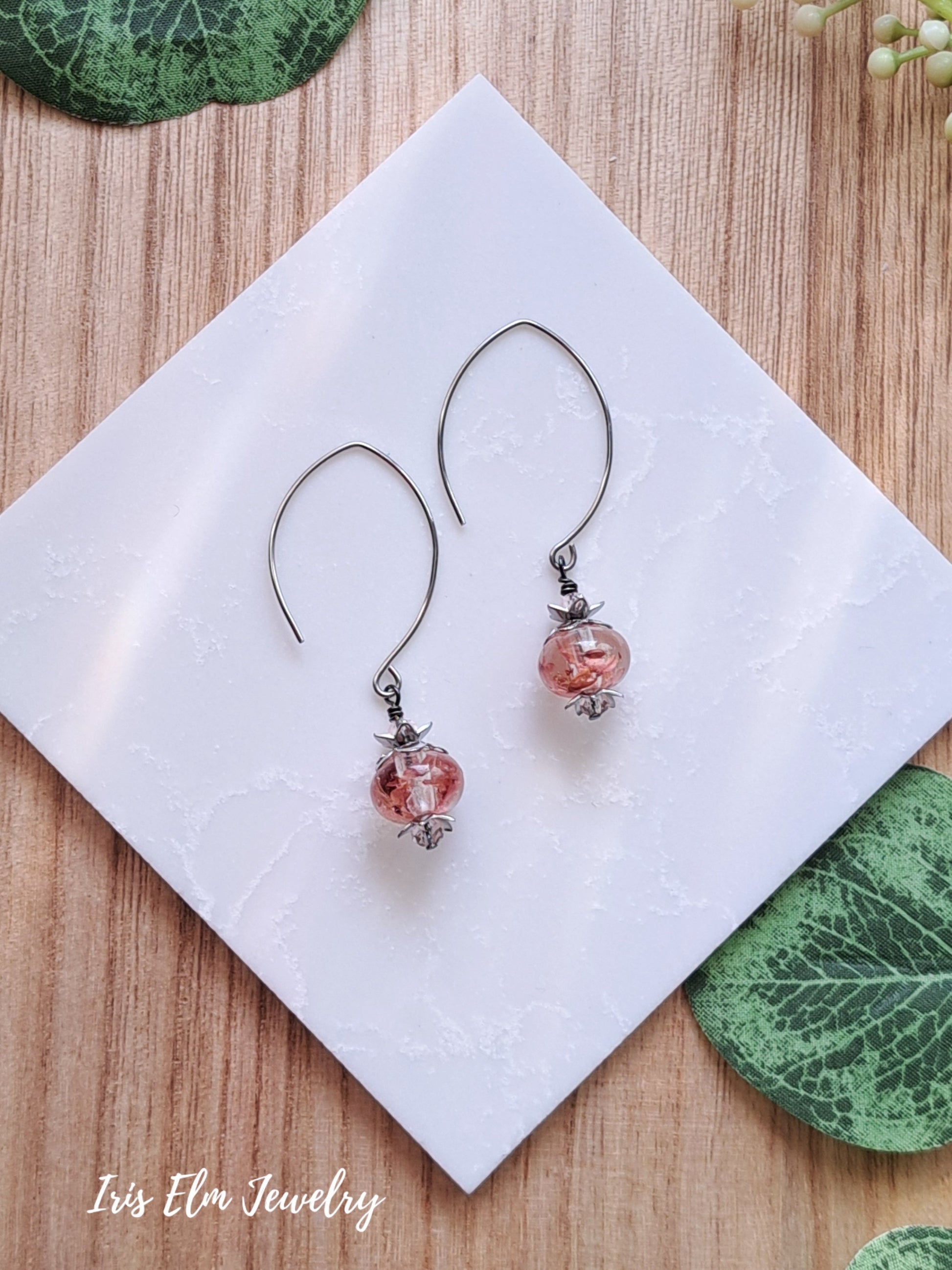 Pair of resin wildflower drop earrings with pink beads on a white napkin with 'Iris Elm Jewelry' branding.