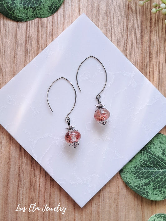 Pair of resin wildflower drop earrings with pink beads on a white napkin with 'Iris Elm Jewelry' branding.