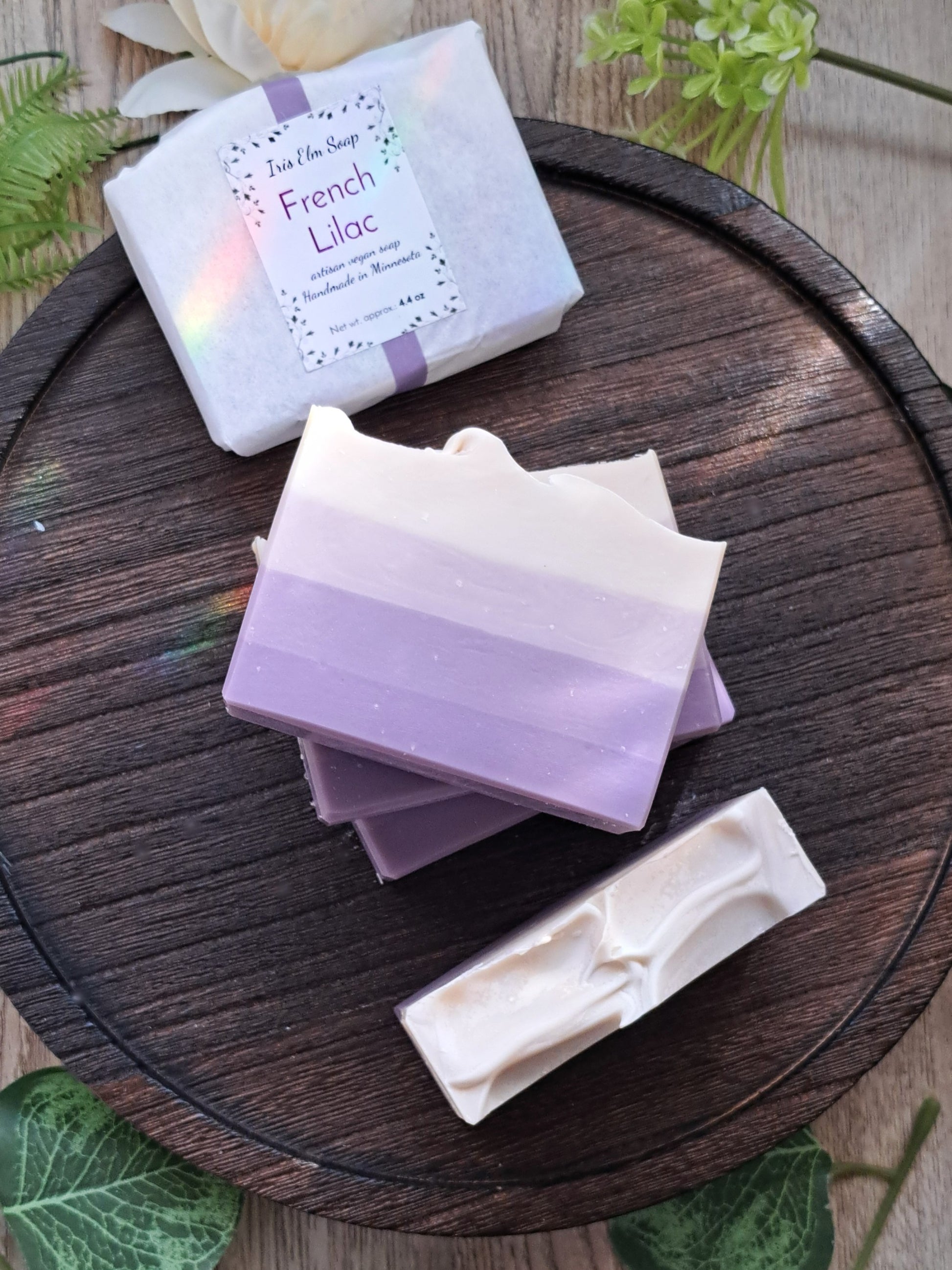 Three bars of French lilac handmade soap with a visible brand label on a wooden surface.