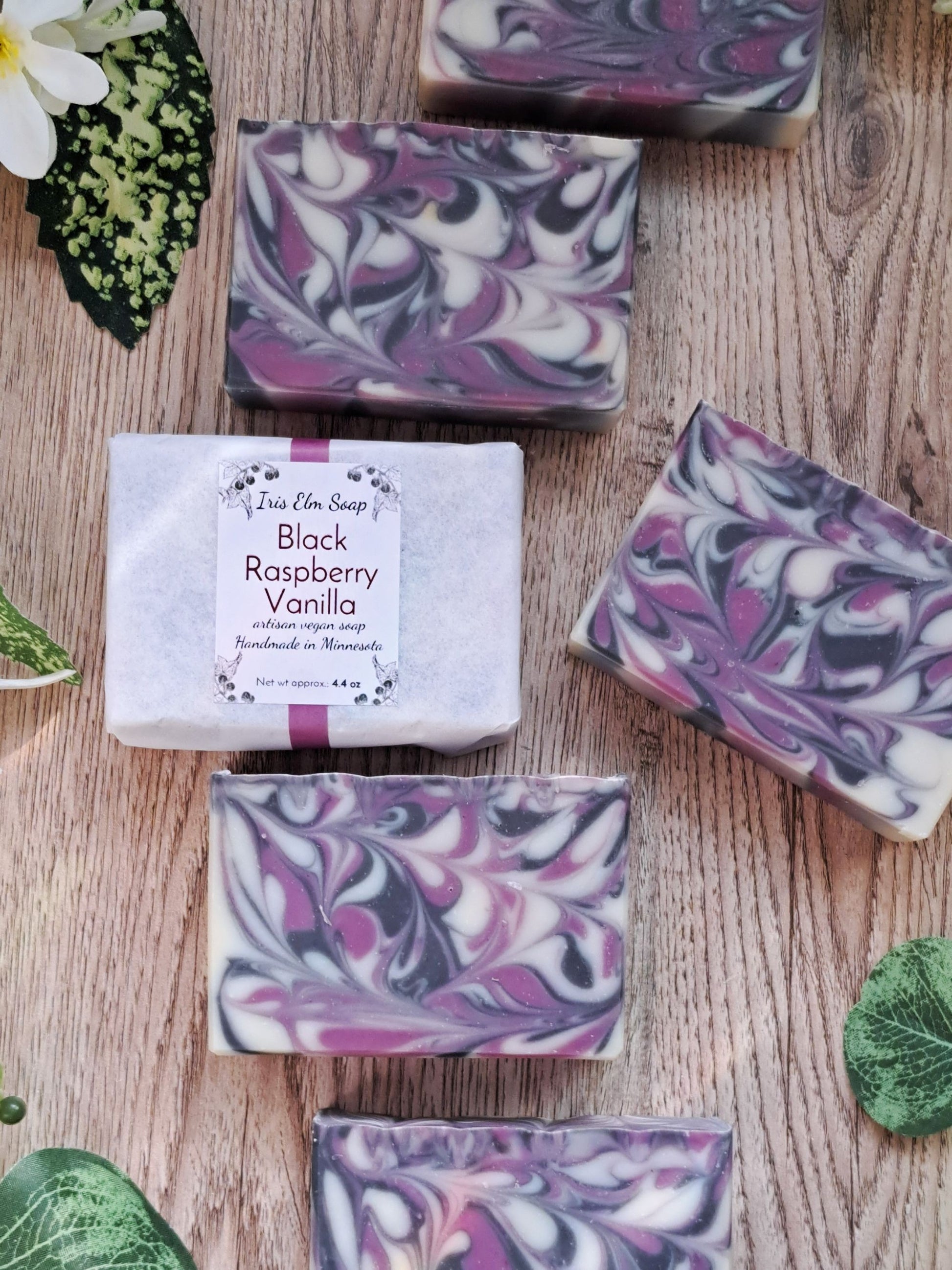 Marbled purple and white soap bars on a wooden surface with a label for 'Black Raspberry Vanilla'.