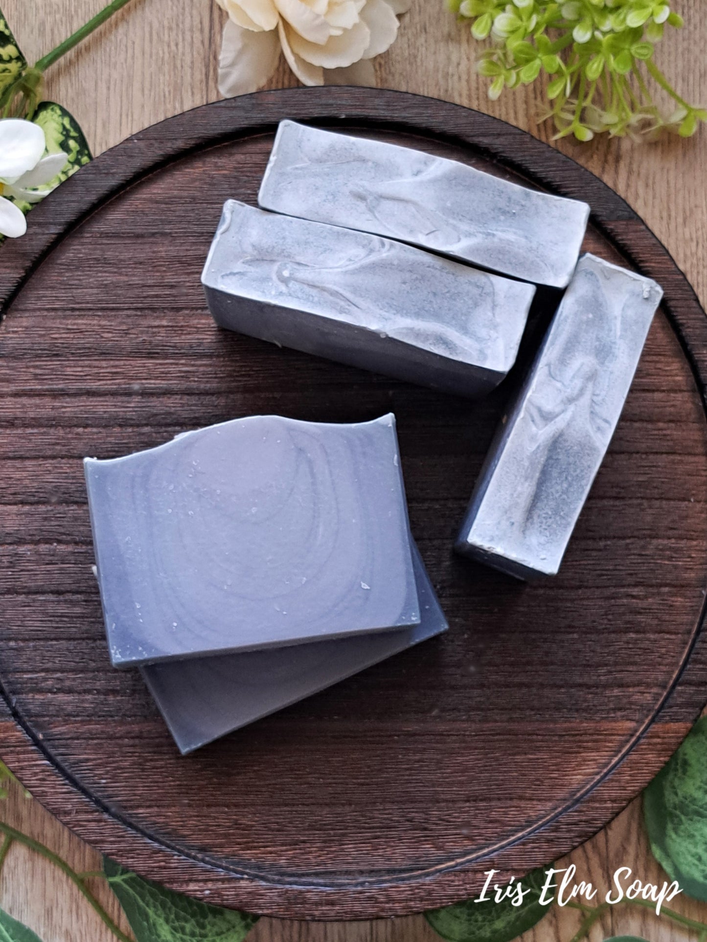 Five bars of cedar musk and lavender handmade soap on a wooden tray with floral decorations