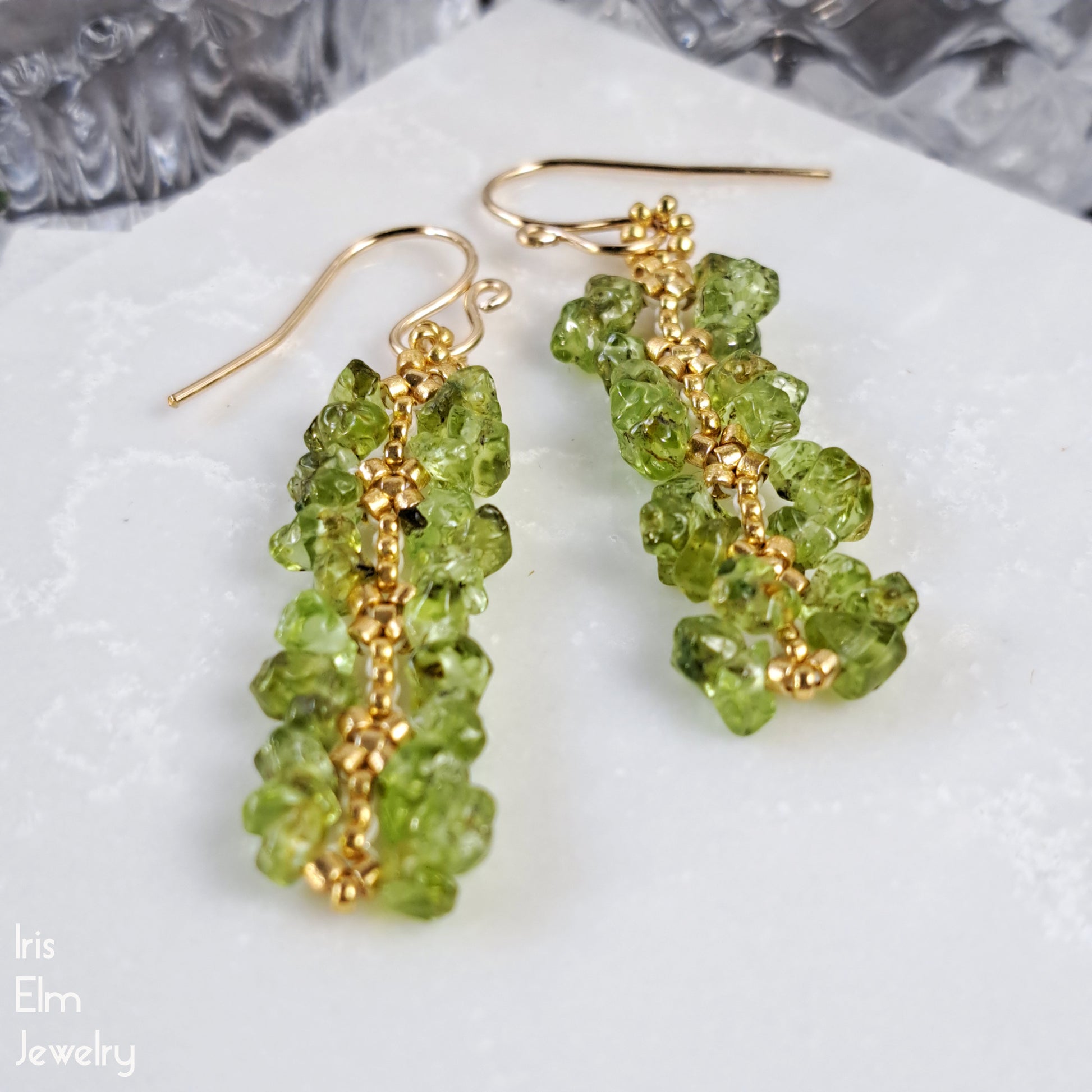 Green peridot gemstone chip beaded earrings with gold hooks on a white surface