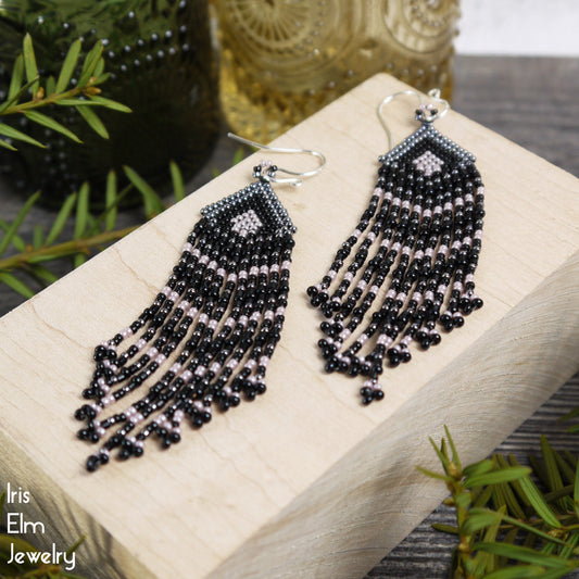 Black beaded earrings on a wooden display block with 'Iris Elm Jewelry' branding.