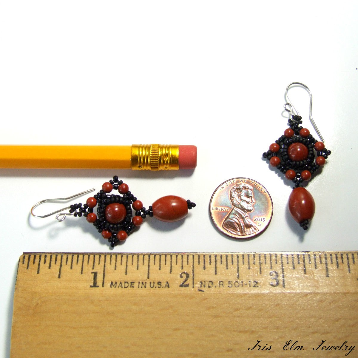 Pair of red jasper beaded earrings next to a pencil and penny on a white background