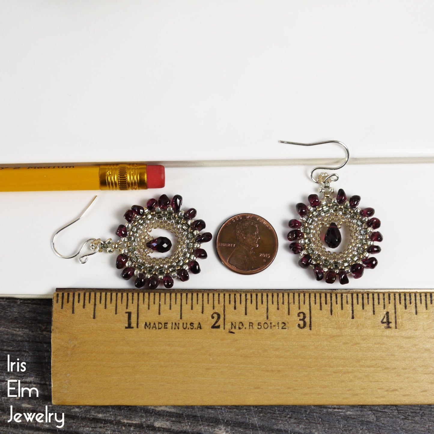 Pair of 2 and 1/8 inch long earrings with red stones and silver hooks on a white background with a ruler for scale.