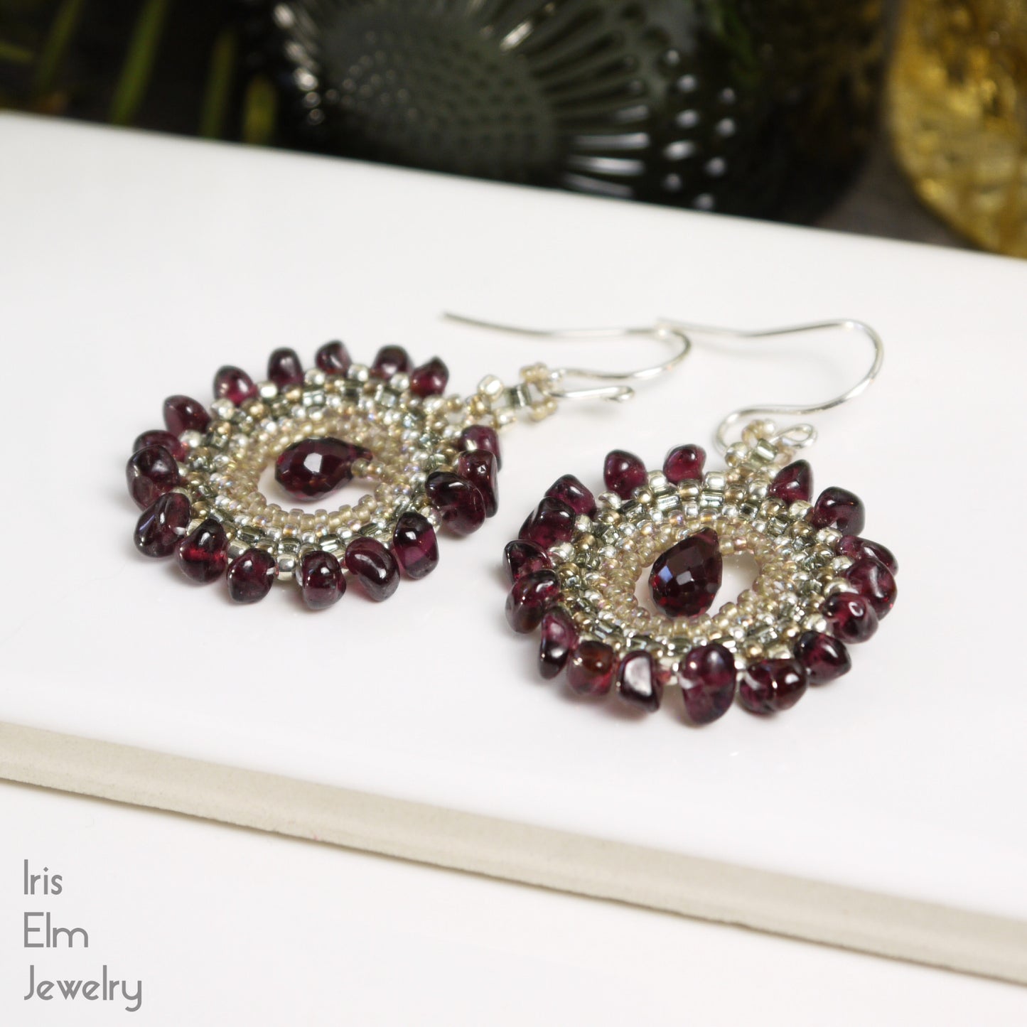 Pair of bohemian beaded red garnet briolette earrings on a white surface with 'Iris Elm Jewelry' branding.