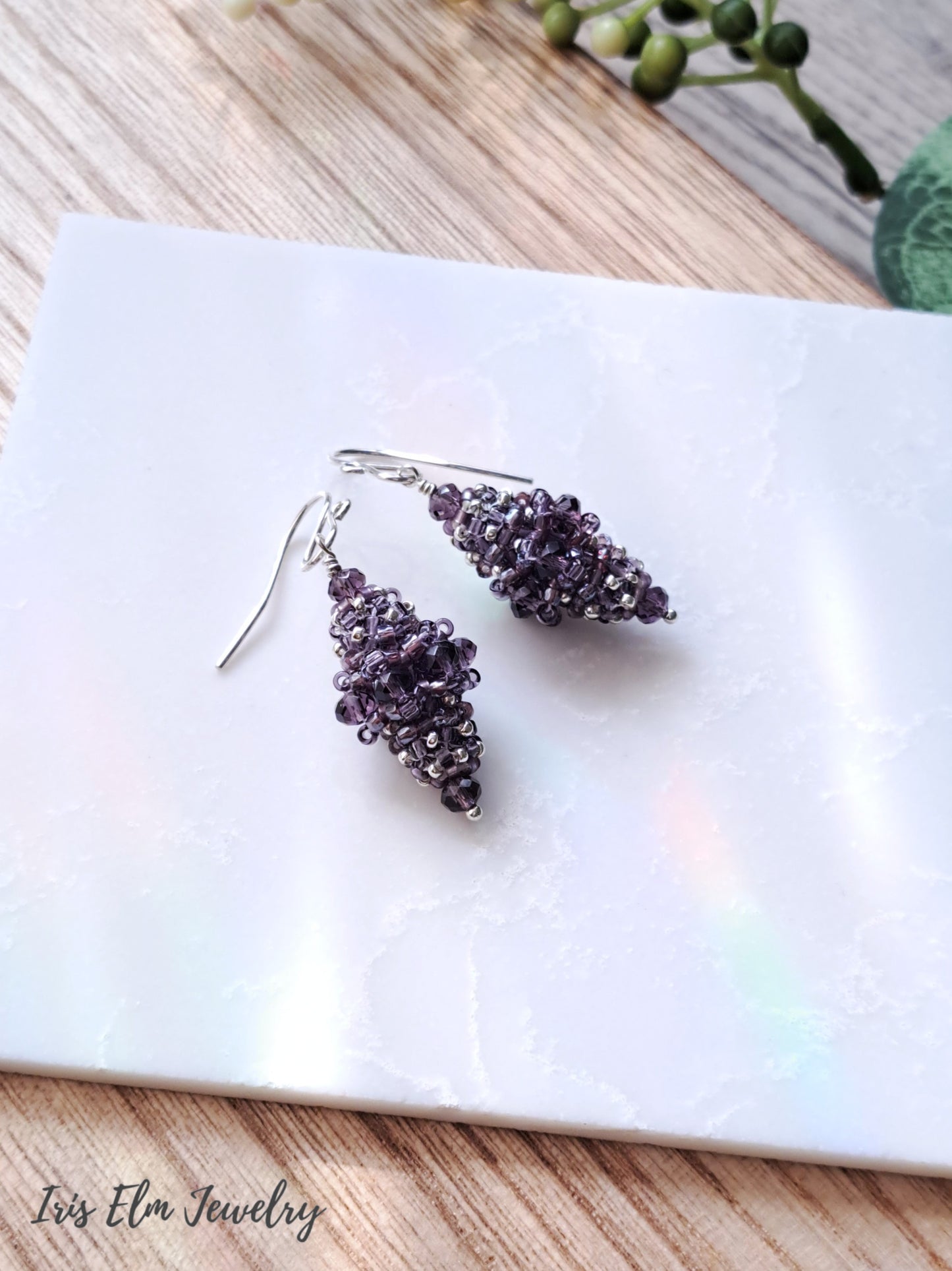 Pair of purple beaded bead glass earrings on a white marble surface with 'Iris Elm Jewelry' branding.
