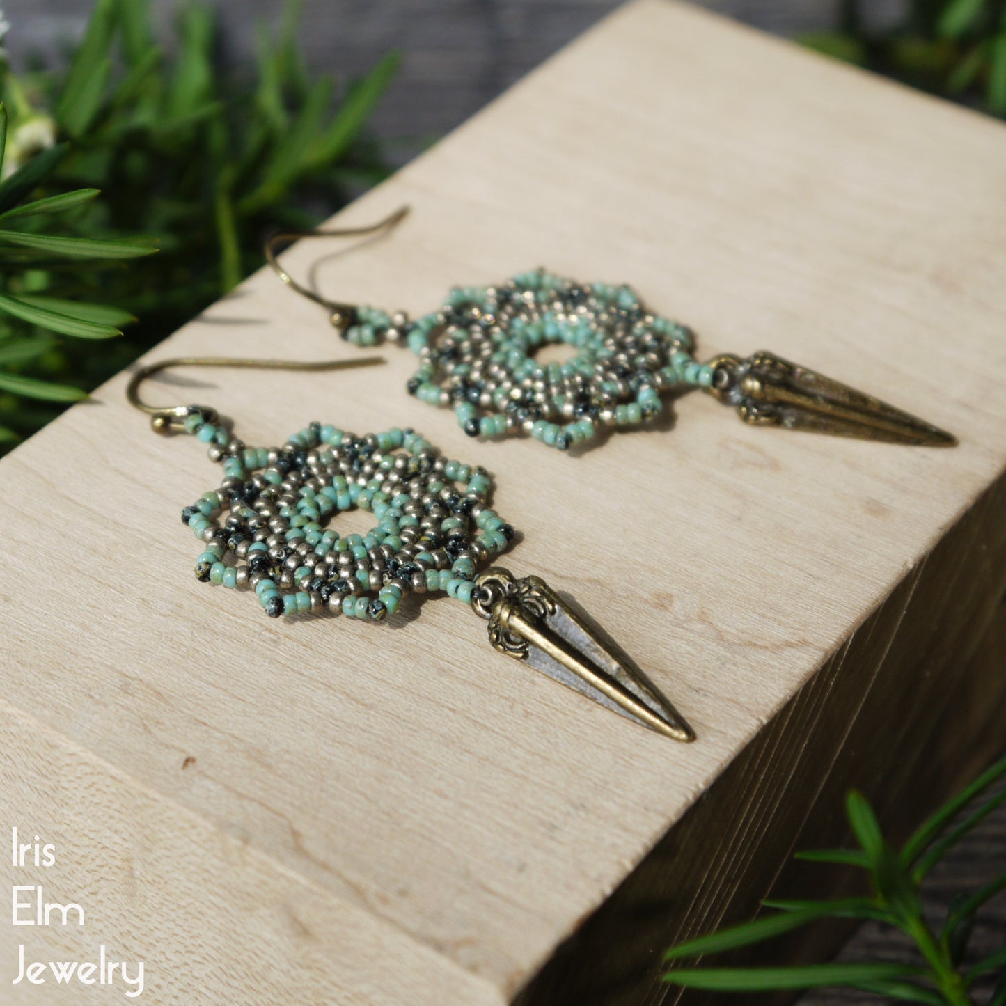Decorative mandala earrings with turquoise glass beads and pyrite colored accents on a wooden surface, branded 'Iris Elm Jewelry'.