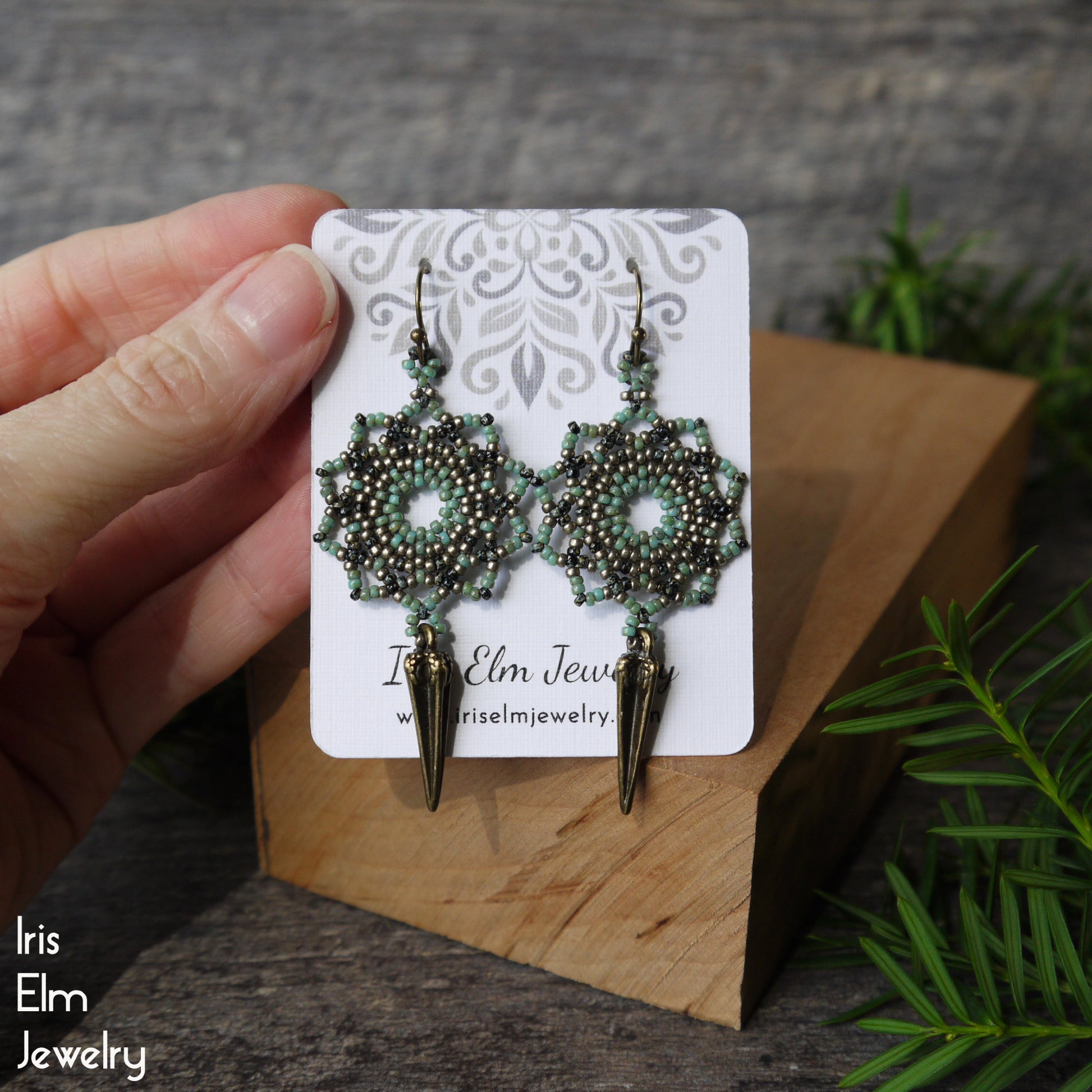handmade beadwork seafoam mandala earrings on a card held by a hand with a natural background
