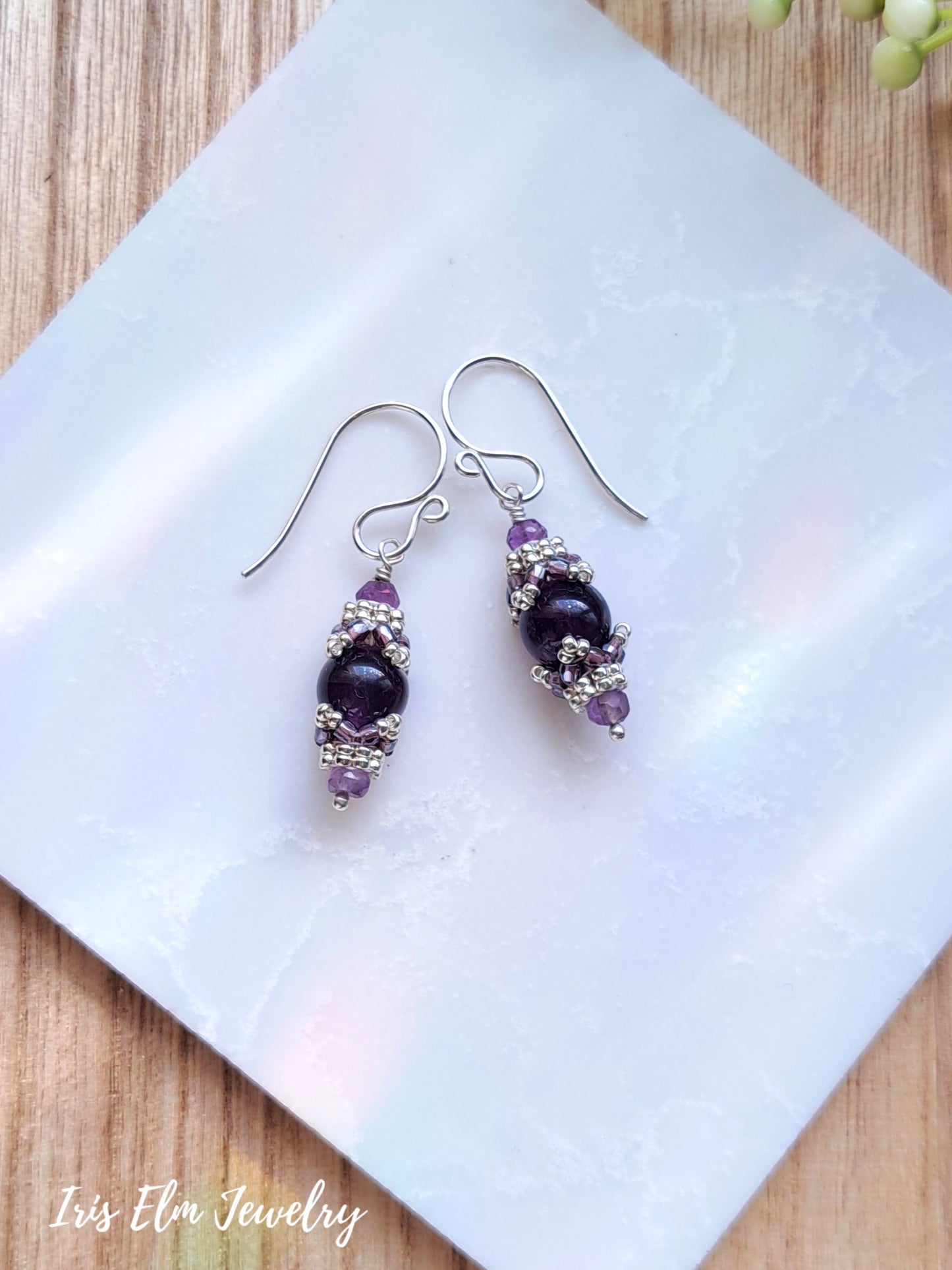 dark purple amethyst beadwork drop earrings on white marble surface