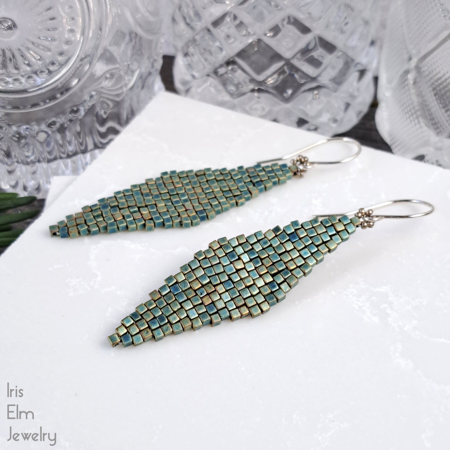 Pair of beaded earrings on a white surface with 'Iris Elm Jewelry' branding.