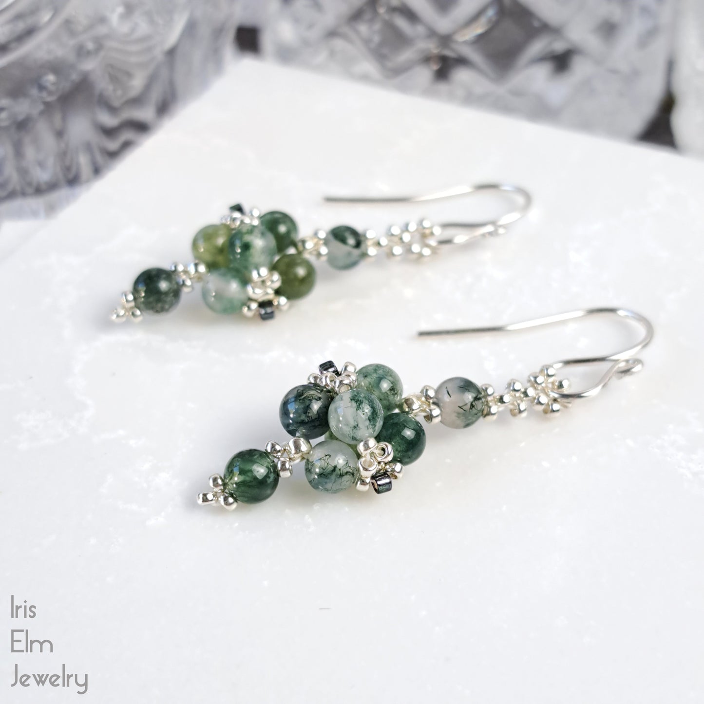 Green beaded earrings on a white surface with 'Iris Elm Jewelry' branding.