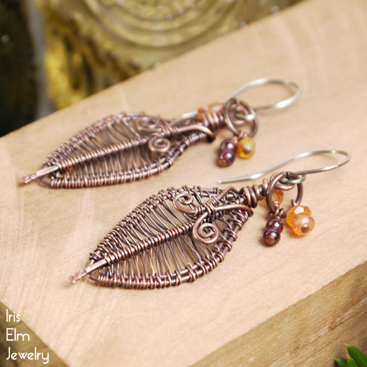 handmade Copper leaf earrings with beads on a wooden surface, featuring 'Iris Elm Jewelry' branding.