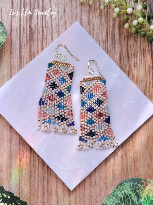 Colorful beaded jewel tone diamond pattern seed bead fringe earrings on a white square with 'Iris Elm Jewelry' branding.
