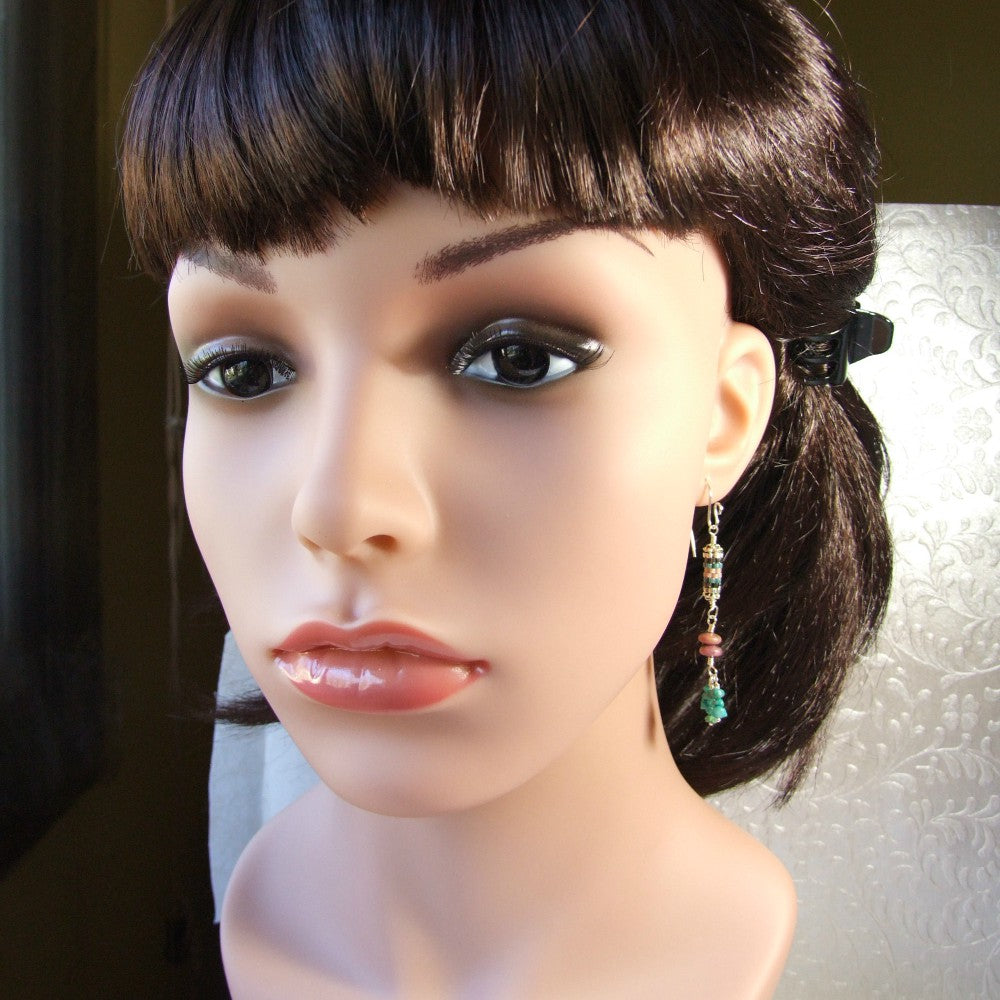 Mannequin head with dark hair styled in a ponytail and wearing gemstone pink stone and turquoise chip earrings.